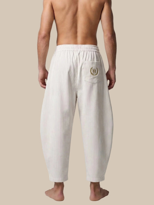 Person wearing white ribbed pants with a logo on a white background