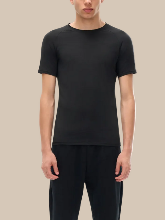 Person wearing a black technical performance t-shirt and pants on a beige background