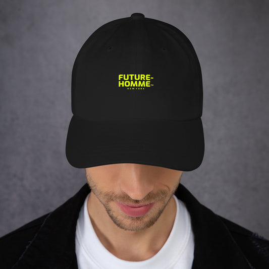 Male model wearing a black baseball cap with yellow Future-Homme logo on a gray background. 