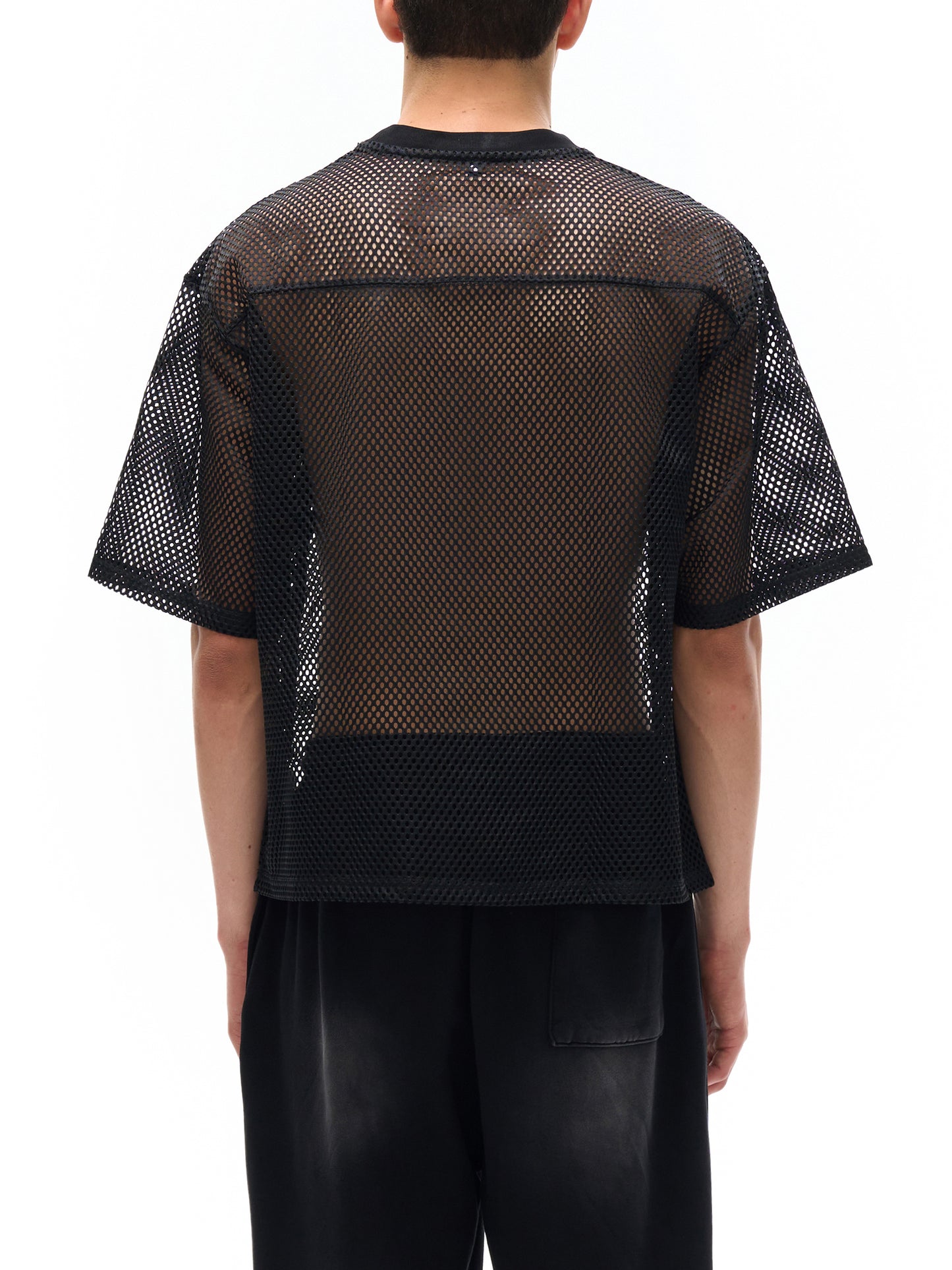 Model wearing the sustainable Future-Homme activewear boxy mesh tee in black backside on a white background. 