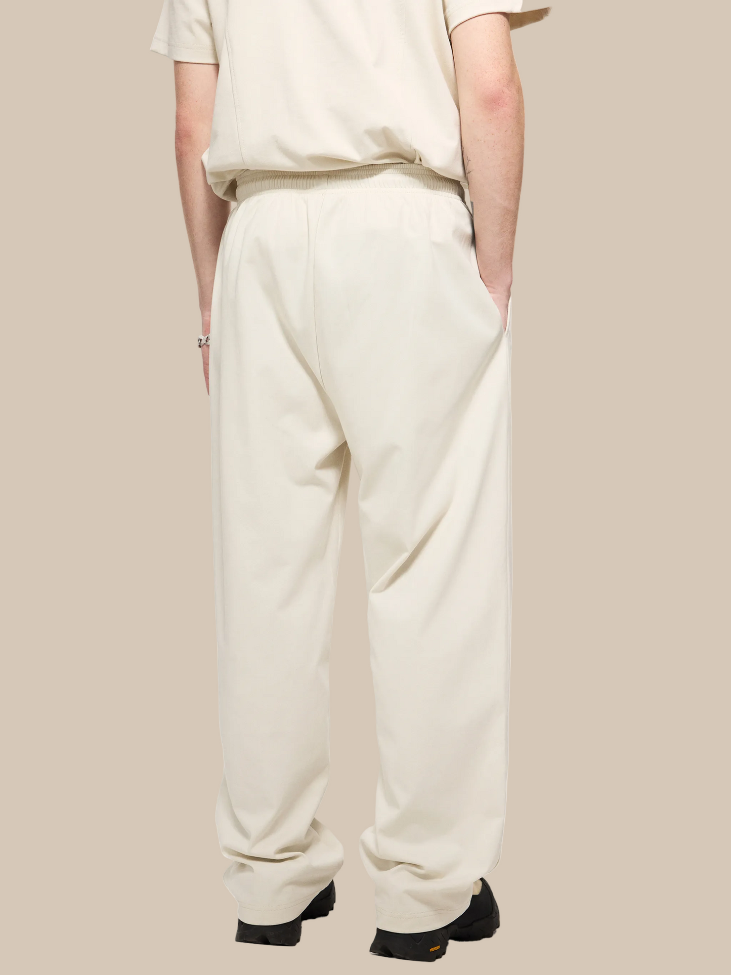 Person wearing beige pants and a matching top on a white background