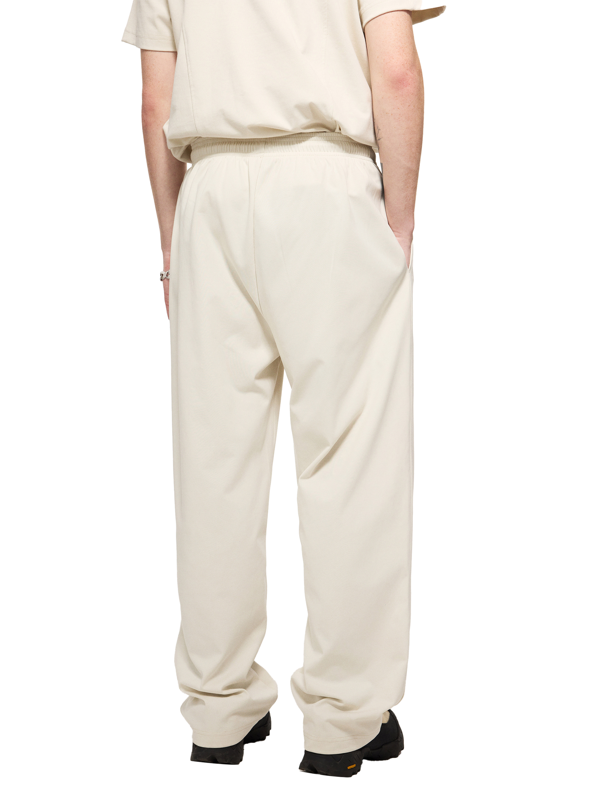 Lower half of a male model wearing a sustainable 240 GSM Future-Homme activewear mesh lined quick dry performance pants in grayish white backside angle on a white background