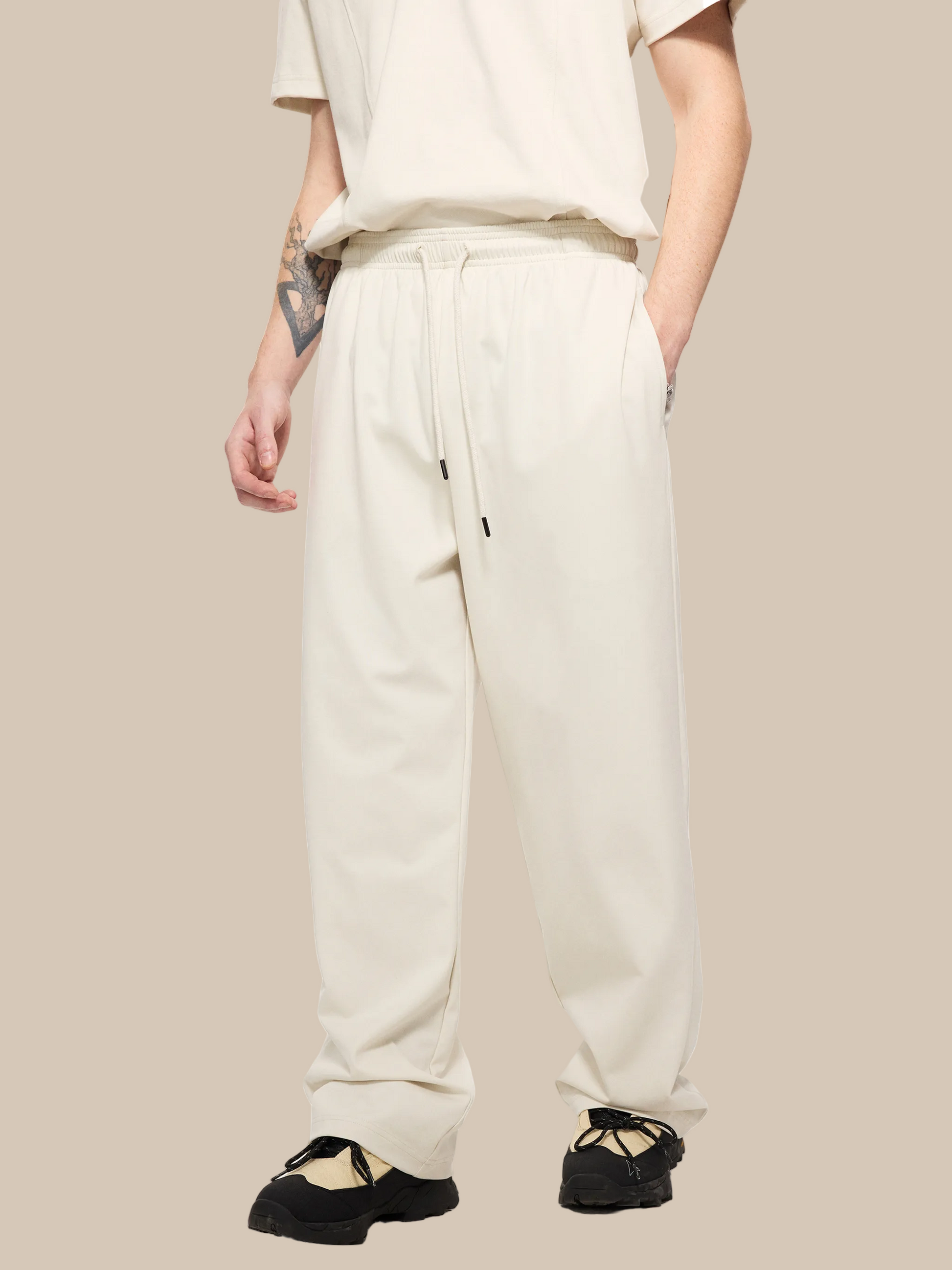 Person wearing beige sweatpants on a white background