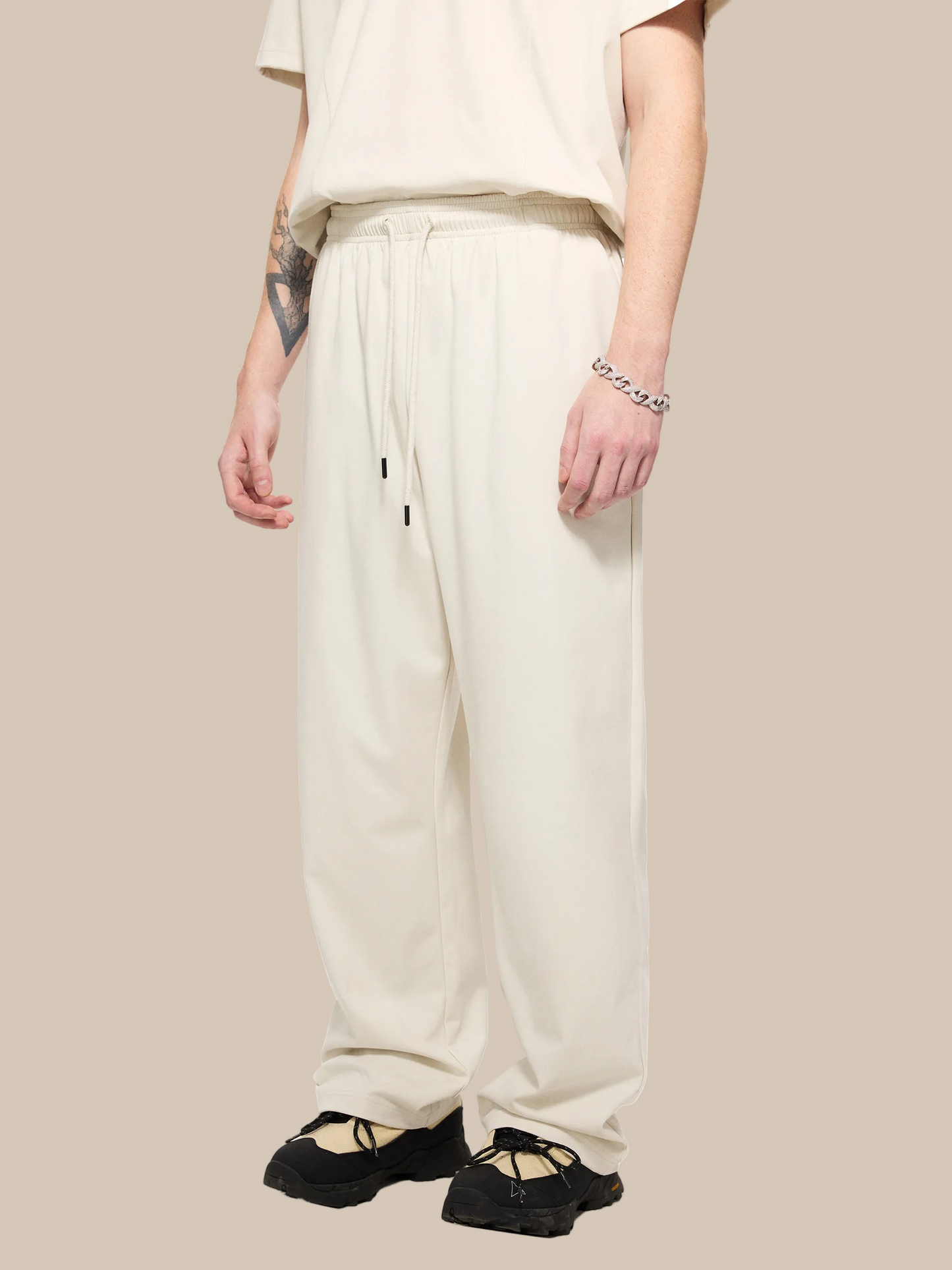 Person wearing beige pants and black shoes on a white background