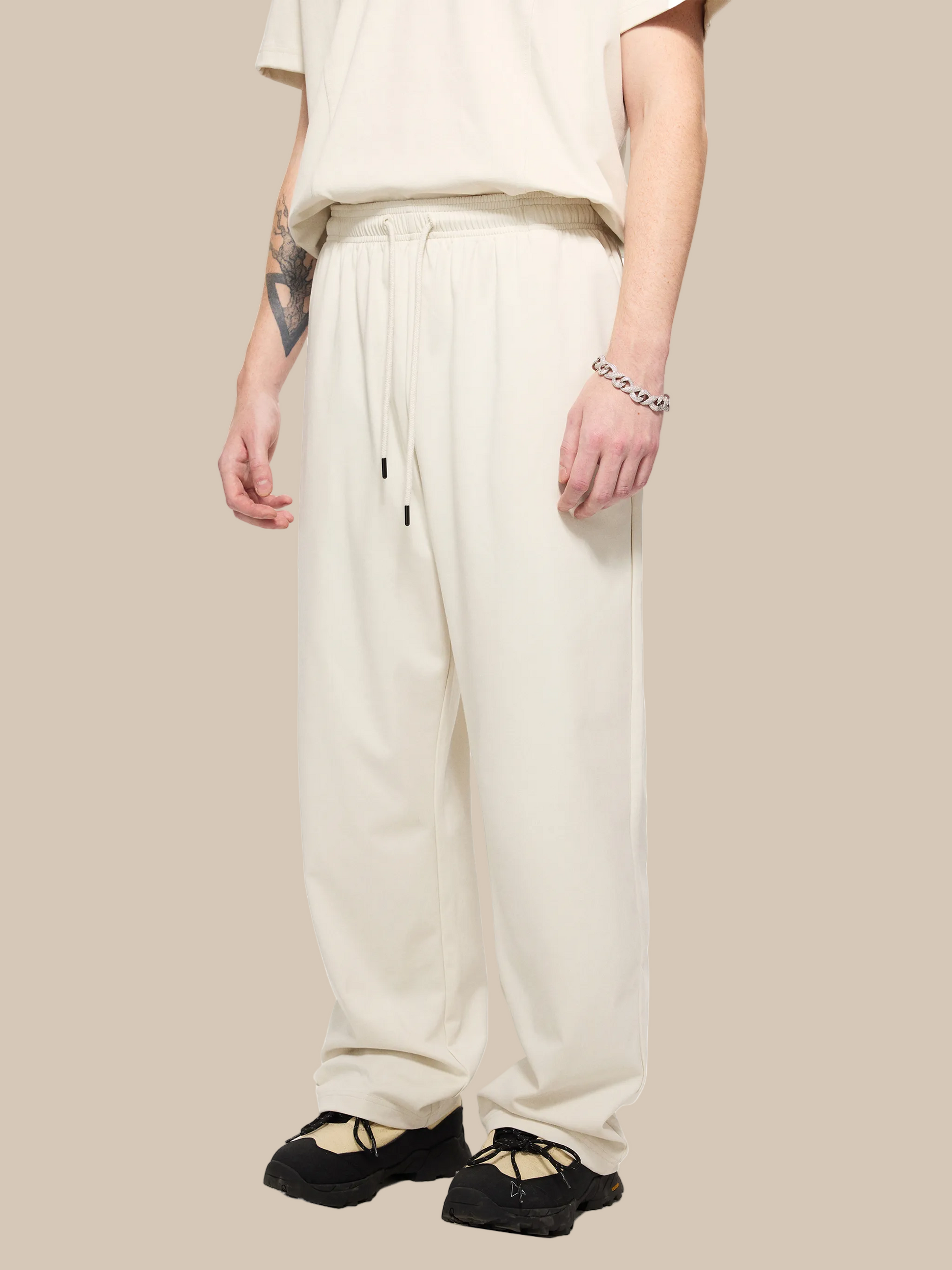 Person wearing beige pants and black shoes on a white background