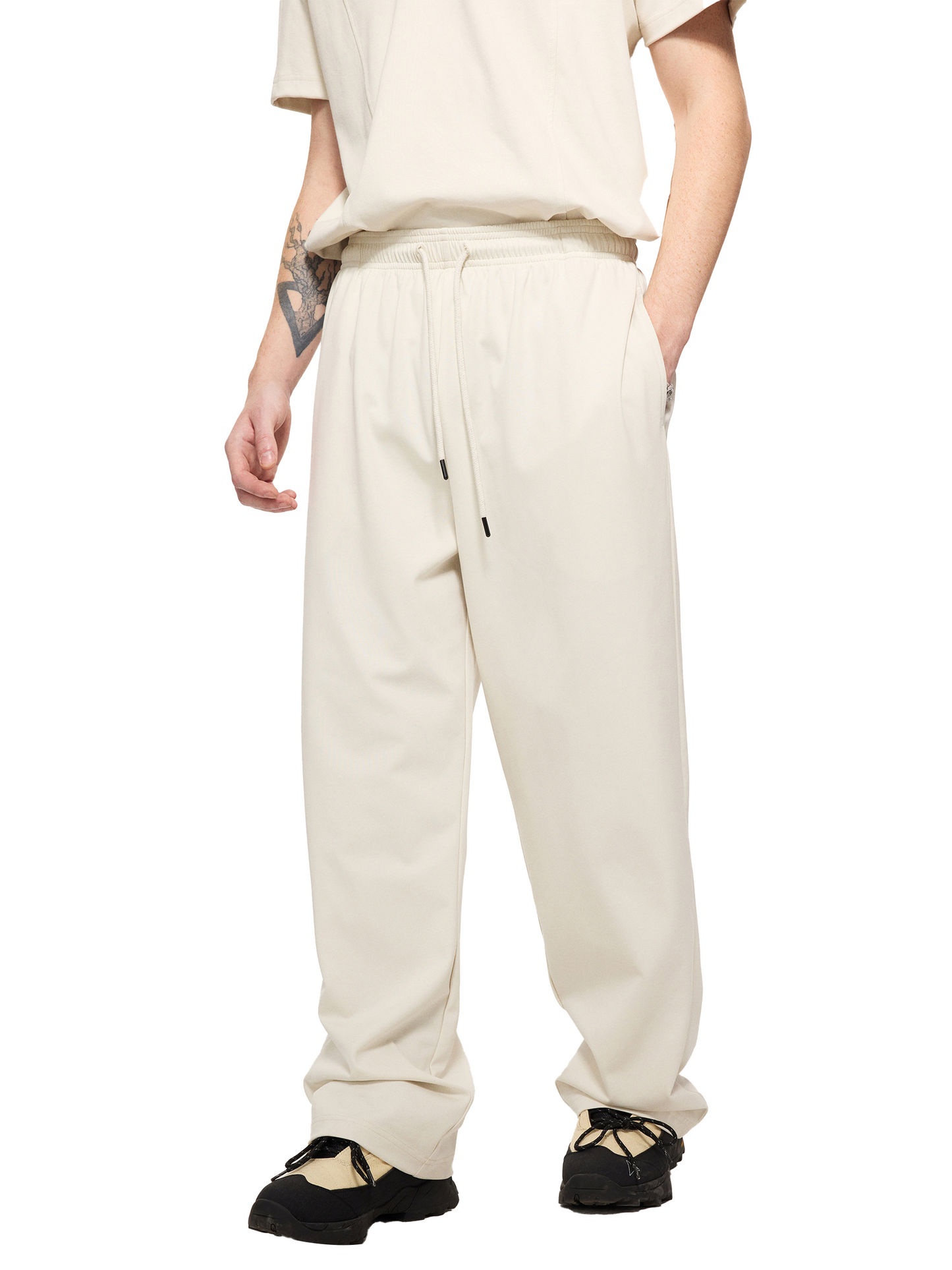 Lower half of a male model wearing a sustainable 240 GSM Future-Homme activewear mesh lined quick dry performance pants in grayish white side angle on a white background
