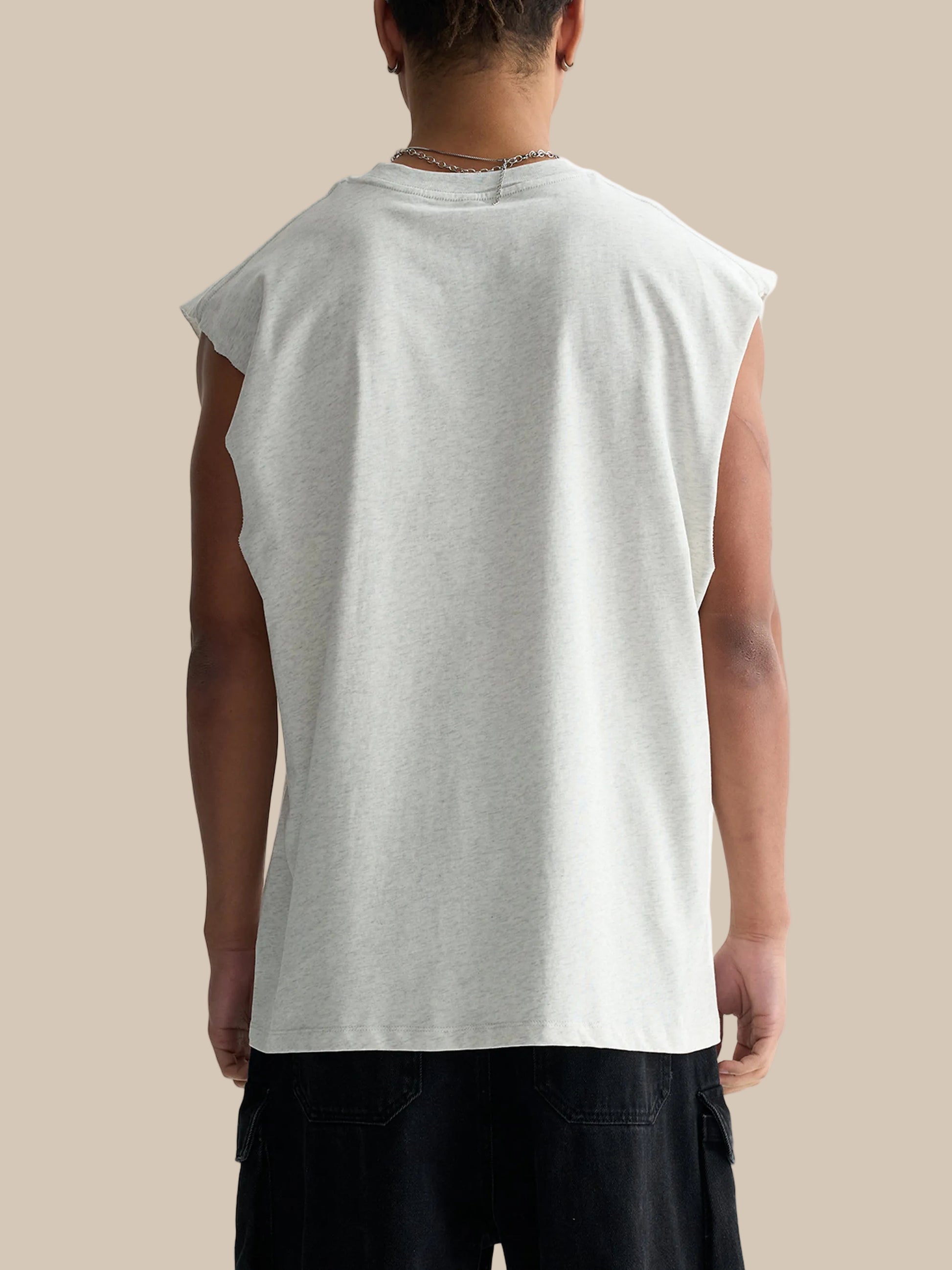 Person wearing a sleeveless gray shirt on a white background