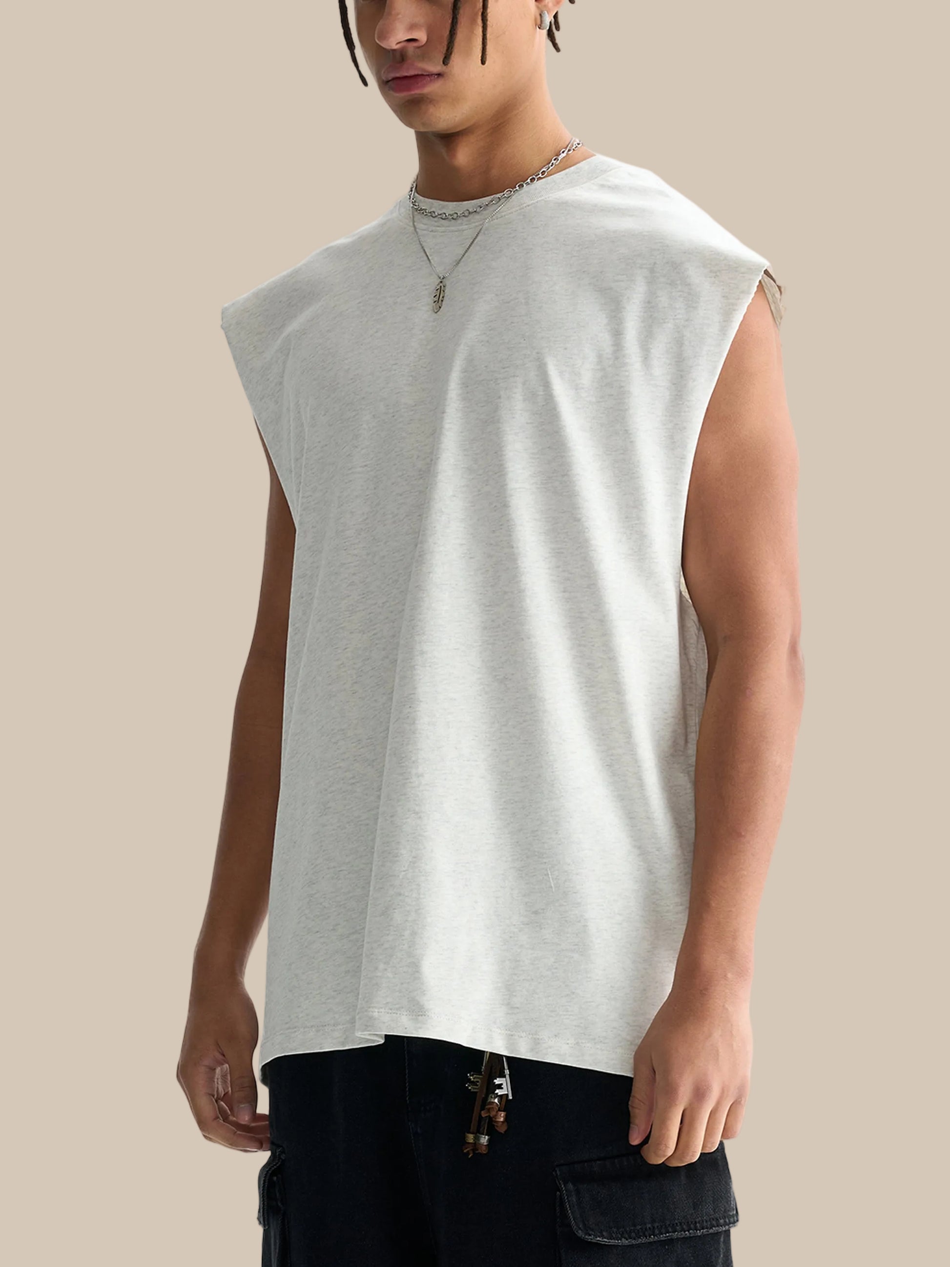 Person wearing a sleeveless light gray shirt on a white background