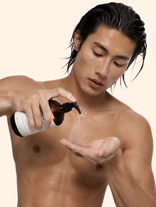 Man applying a product from a bottle to his palm on a white background