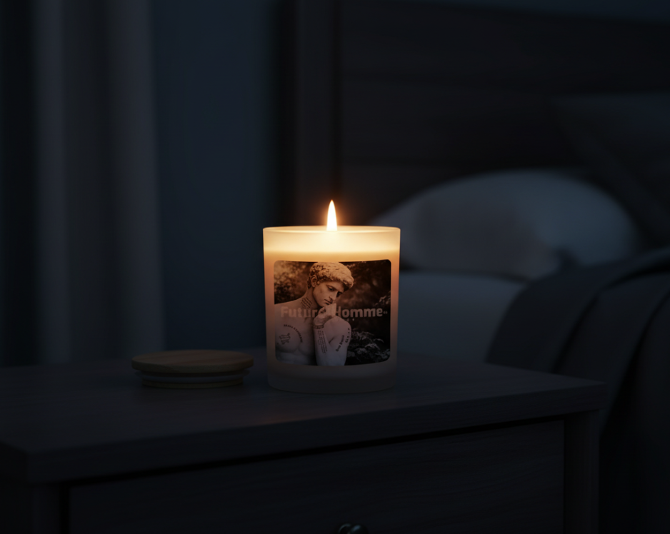 A lit Future-Homme candle sitting on a nightstand in a dark bedroom