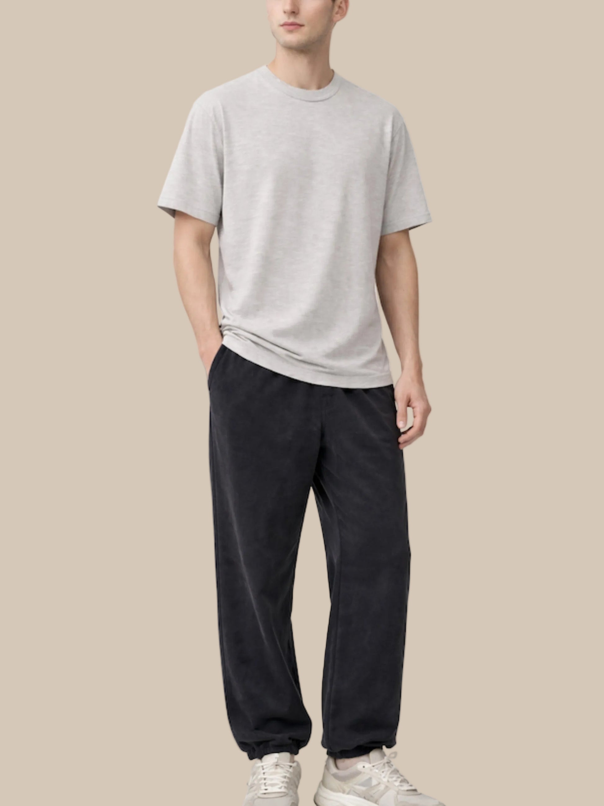 Person wearing a gray t-shirt and black pants on a white background