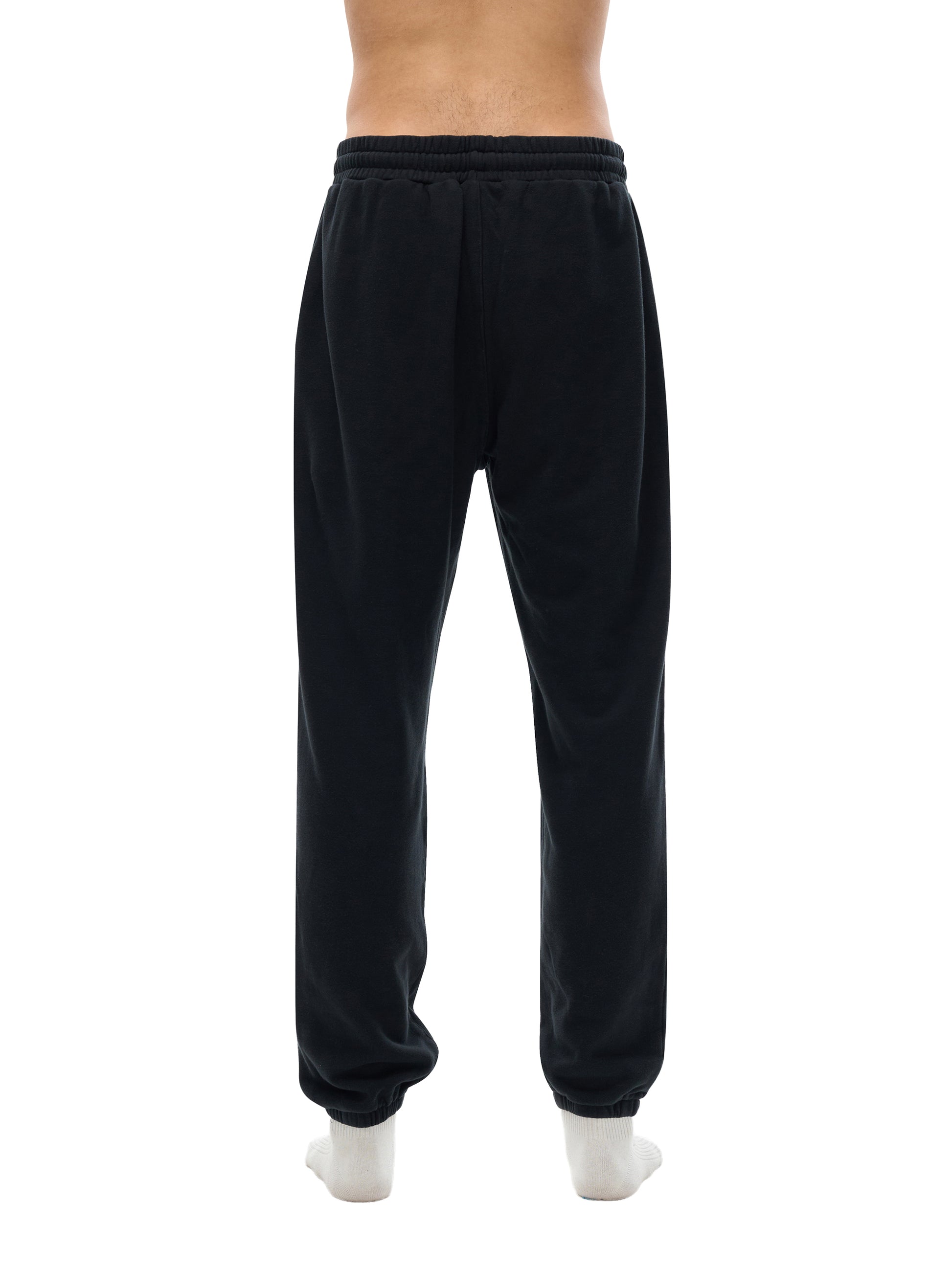 Lower half of model wearing sustainable 360 GSM Future-Homme daily uniform cotton fleece sweatpants backside in black on a white background. 