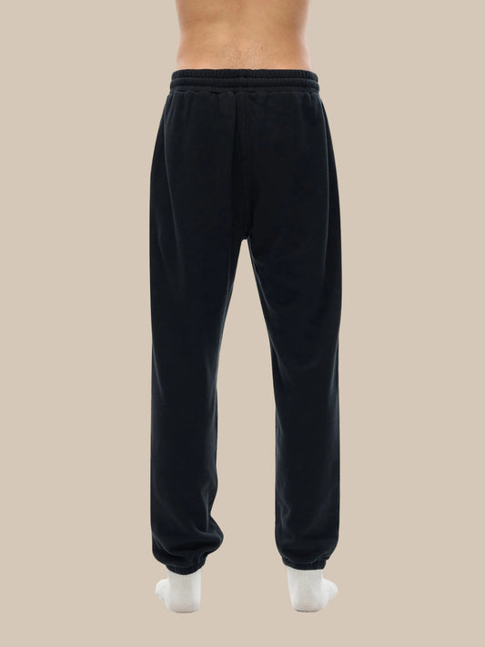 Lower half of model wearing sustainable 360 GSM Future-Homme daily uniform cotton fleece sweatpants backside in black on a white background. 