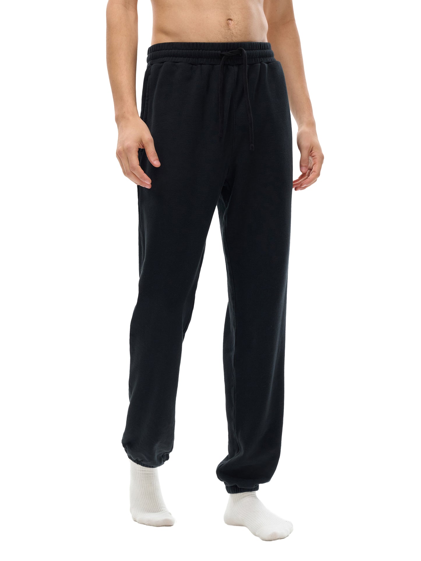 Lower half of model wearing sustainable 360 GSM Future-Homme daily uniform cotton fleece sweatpants in black walking on a white background. 