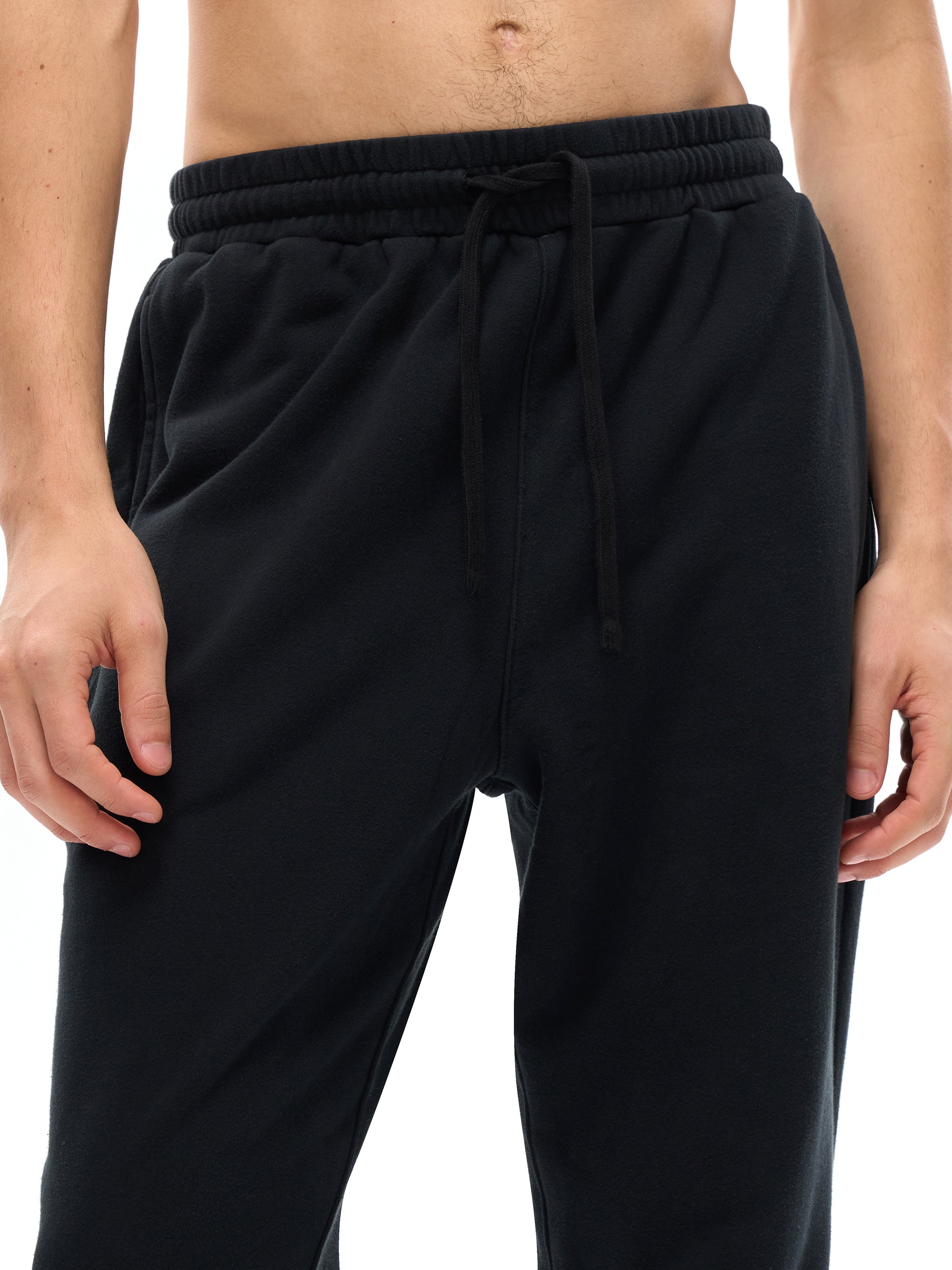 Lower half of model wearing sustainable 360 GSM Future-Homme daily uniform cotton fleece sweatpants frontside in black on a white background. 