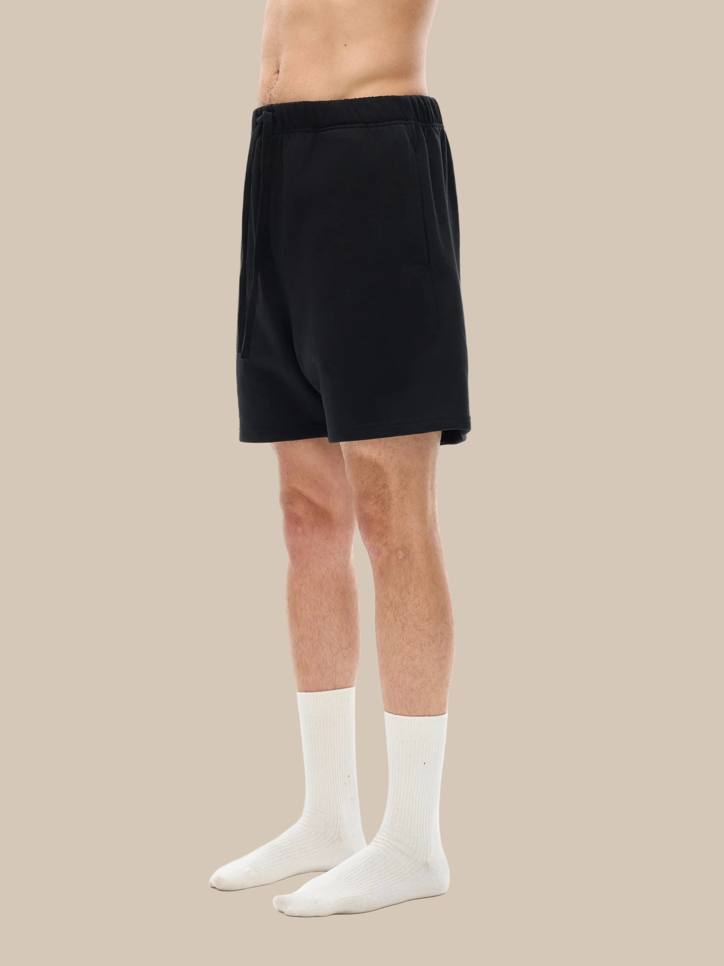 Person wearing black shorts and white socks on a white background