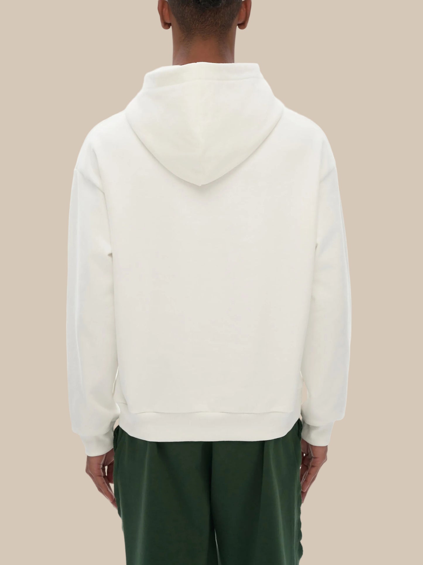 Person wearing a white hoodie with green pants on a white background