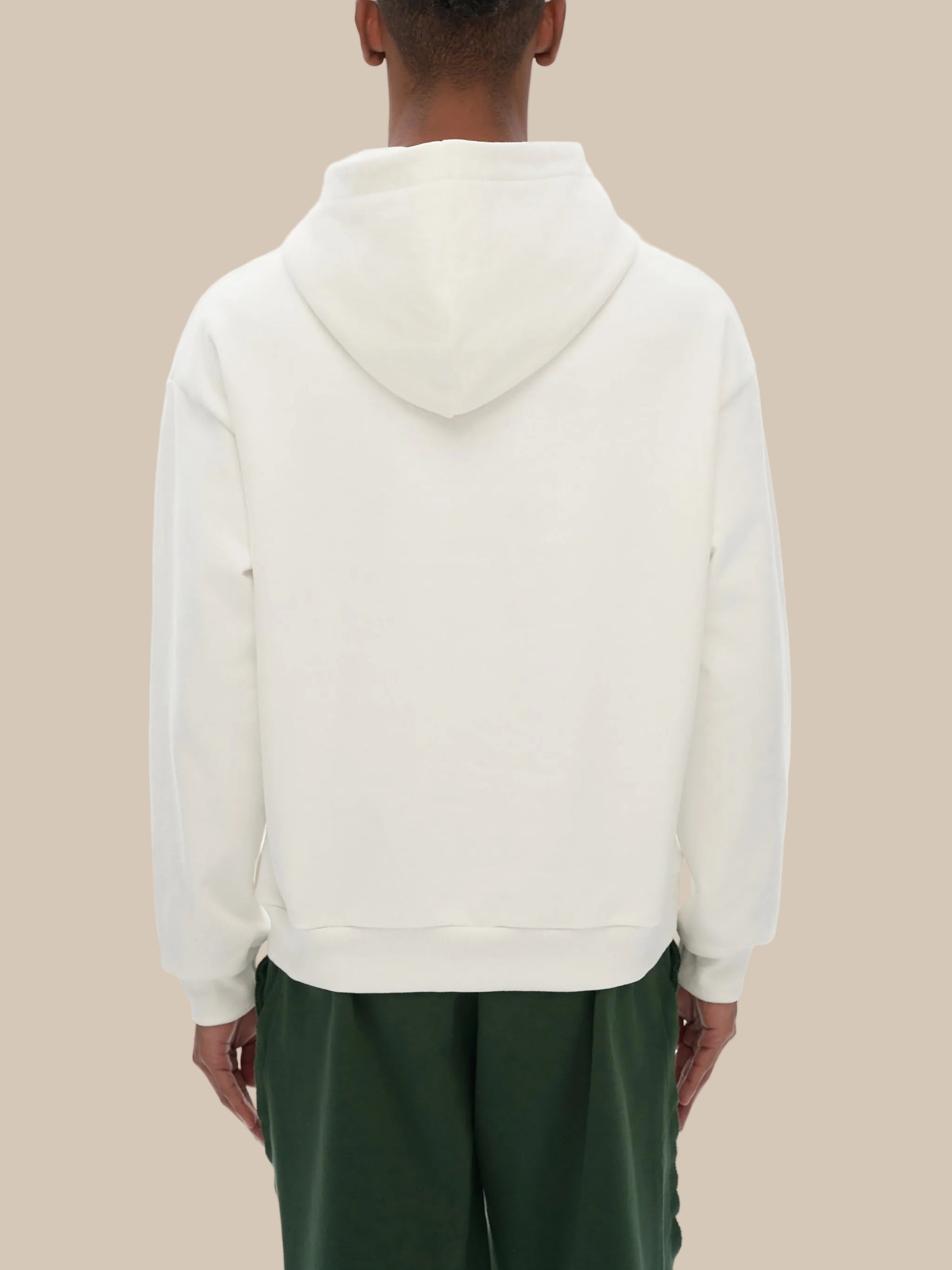 Person wearing a white hoodie with green pants on a white background