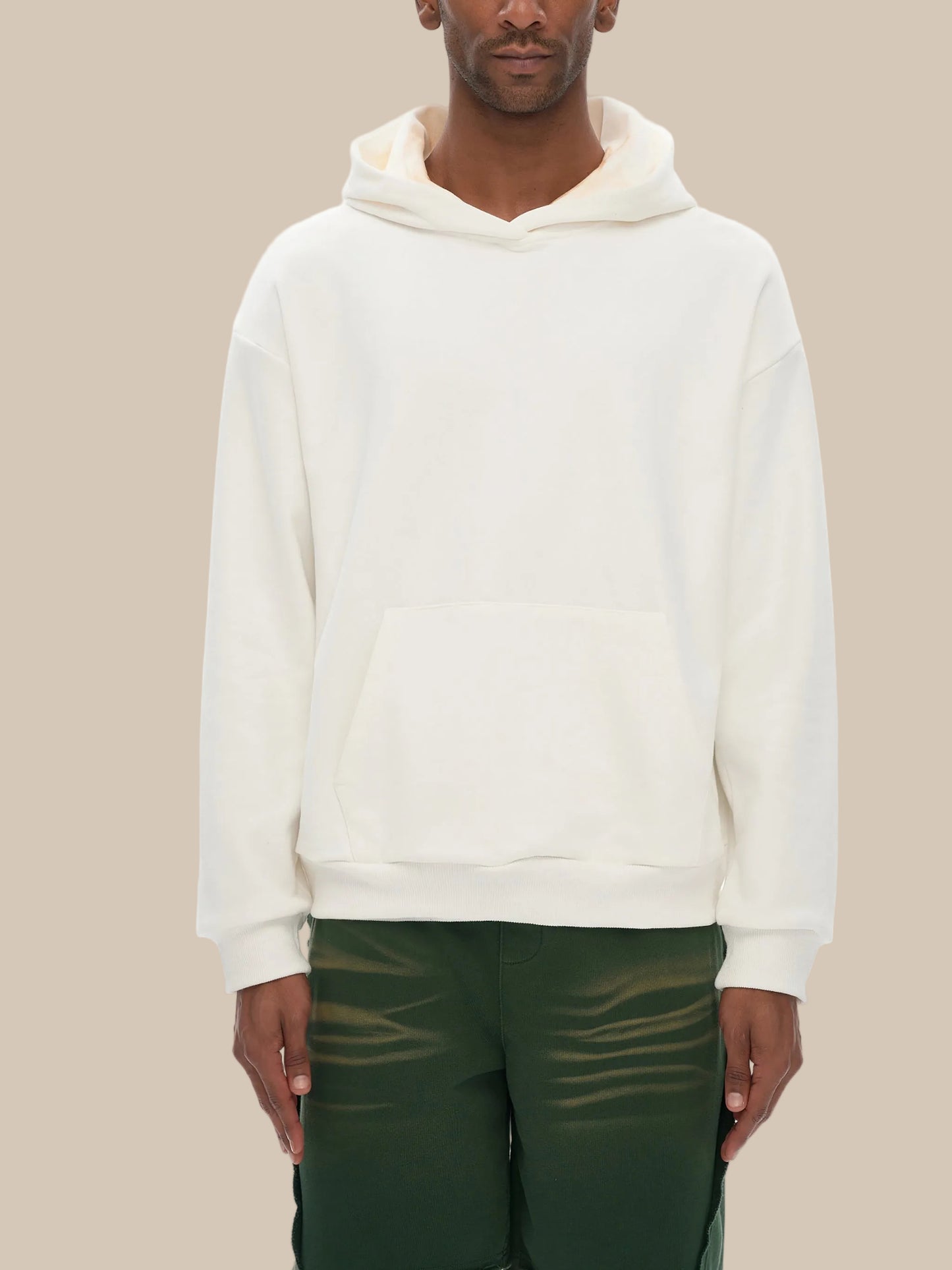 Person wearing a white hoodie and green pants on a white background