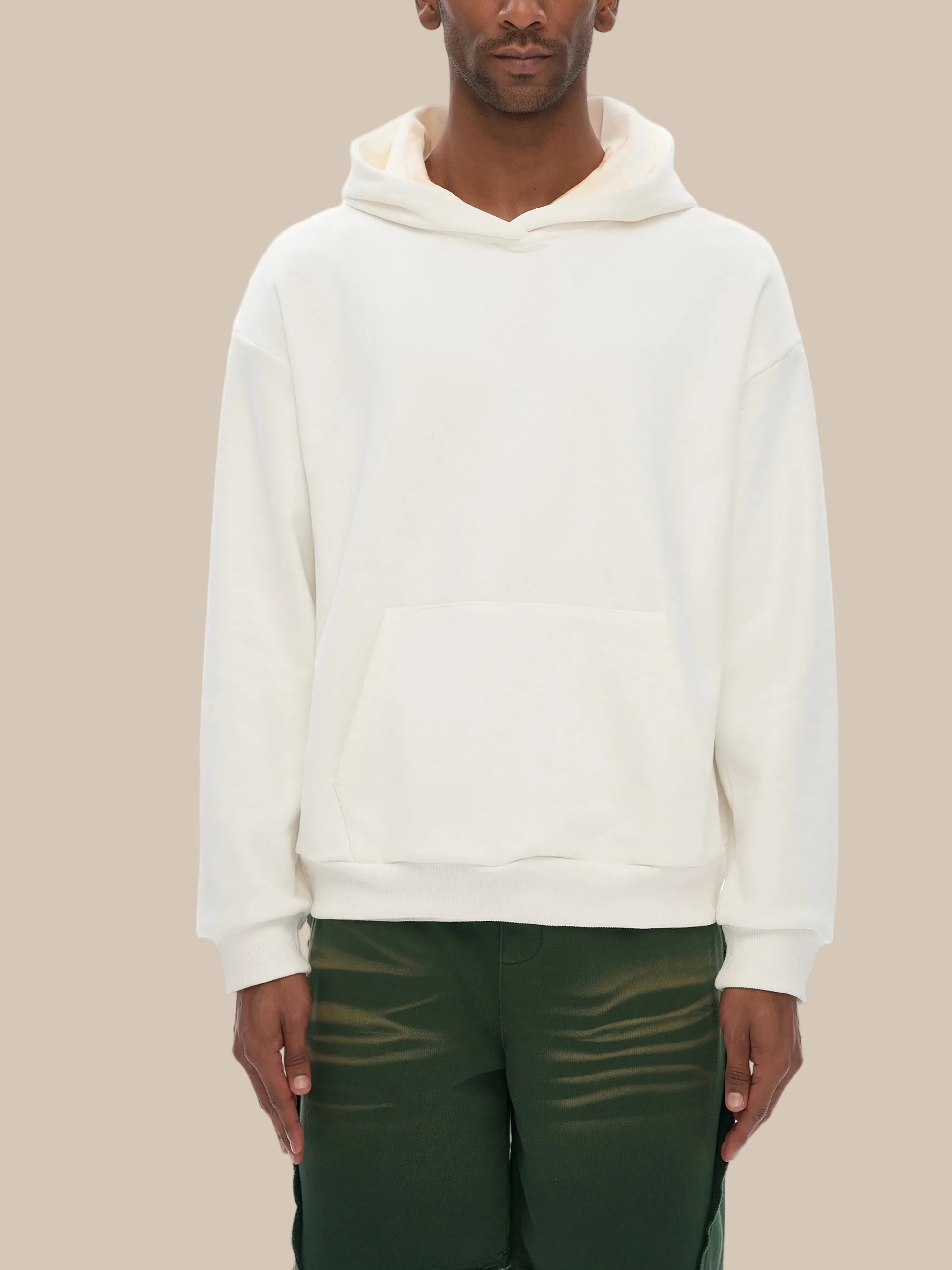 Person wearing a white hoodie and green pants on a white background