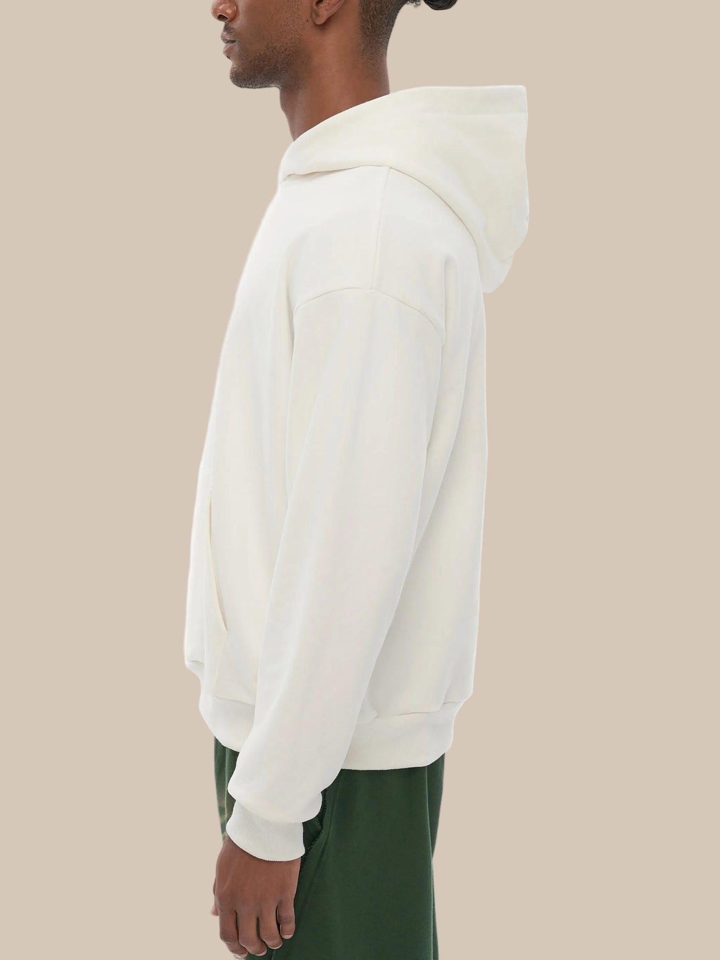 Person wearing a white hoodie with green pants on a white background