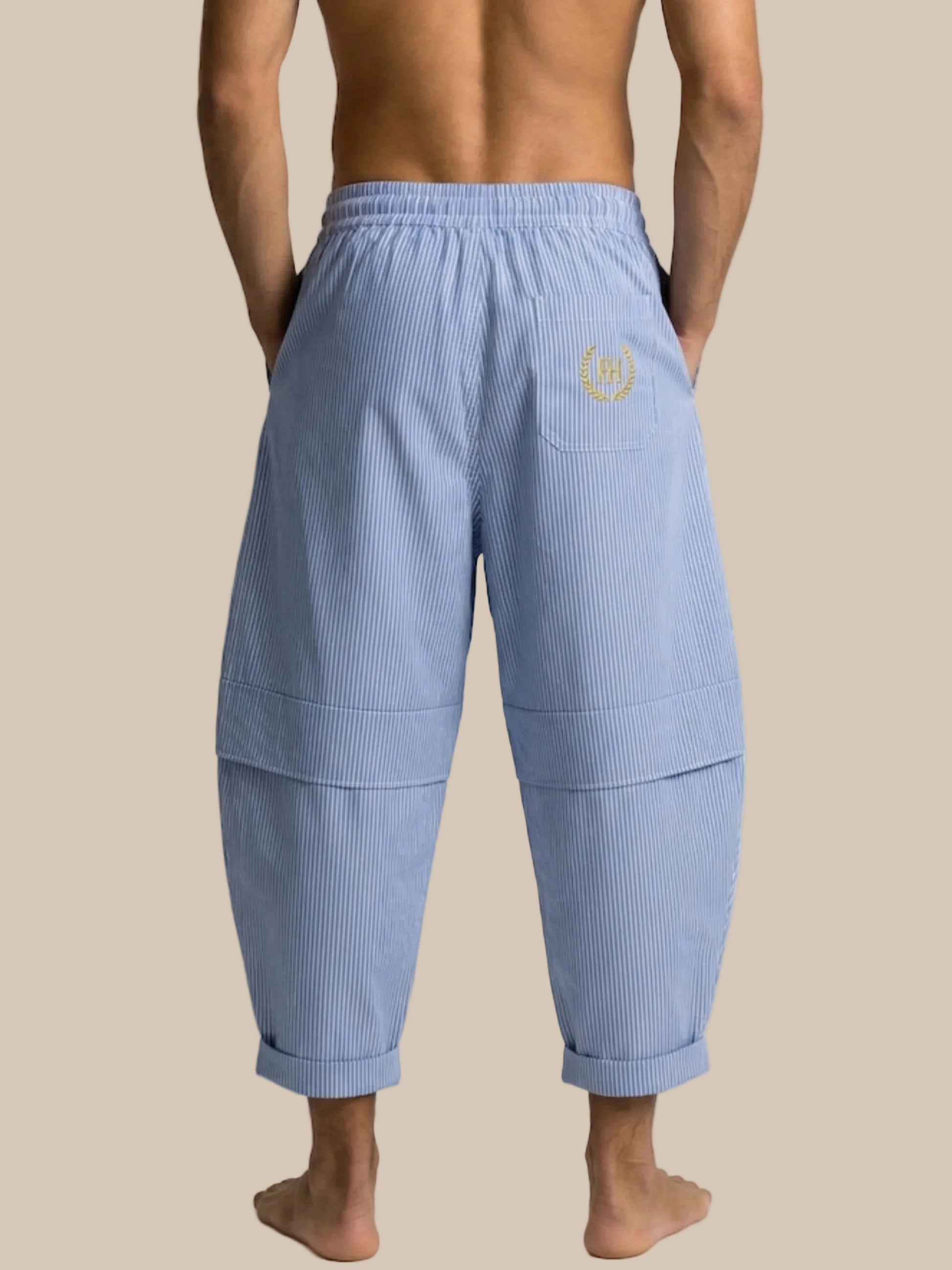 Blue ribbed pants with a logo on the back pocket worn by a person on a white background