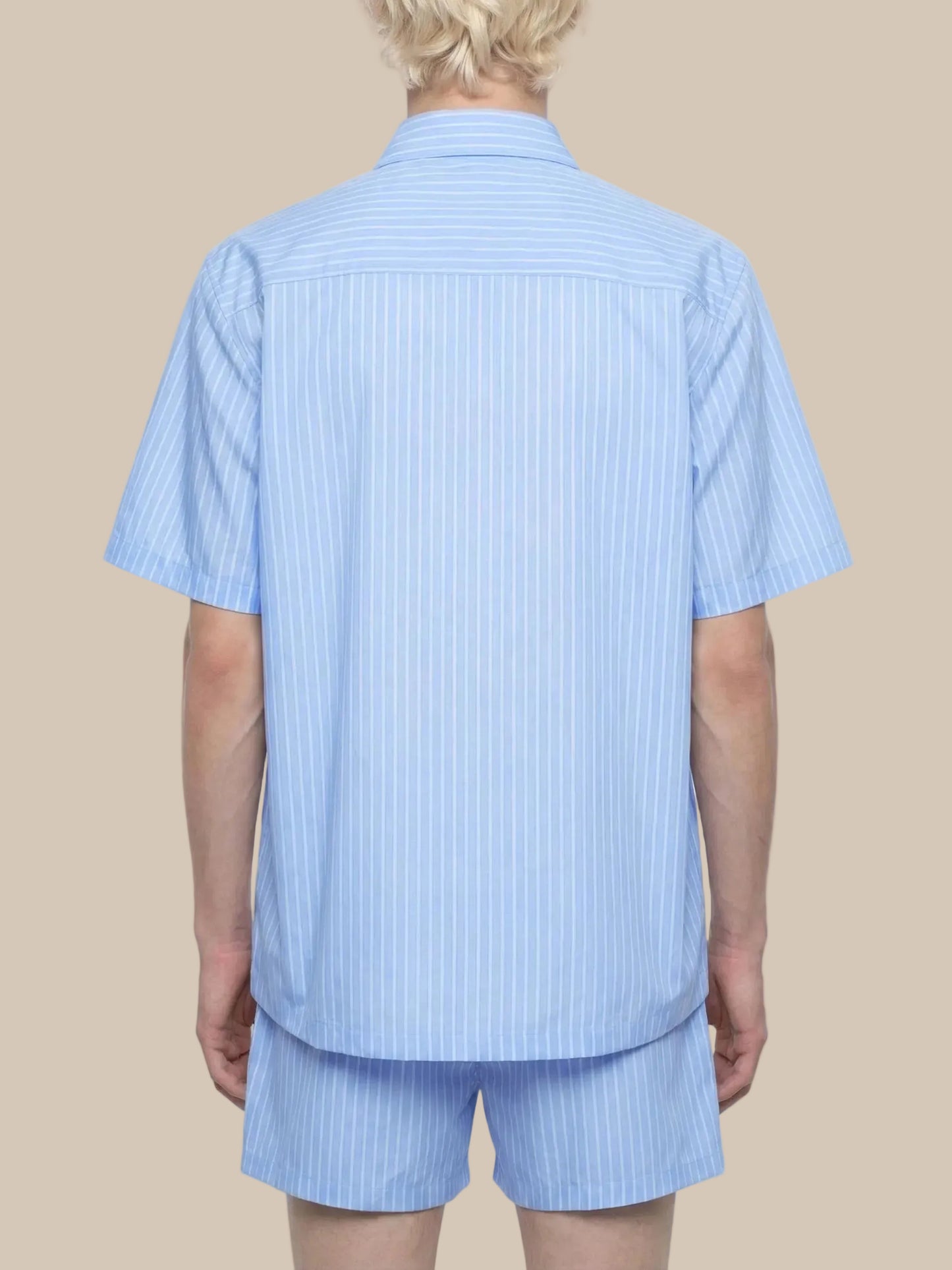 Person wearing a light blue striped shirt and shorts set on a white background