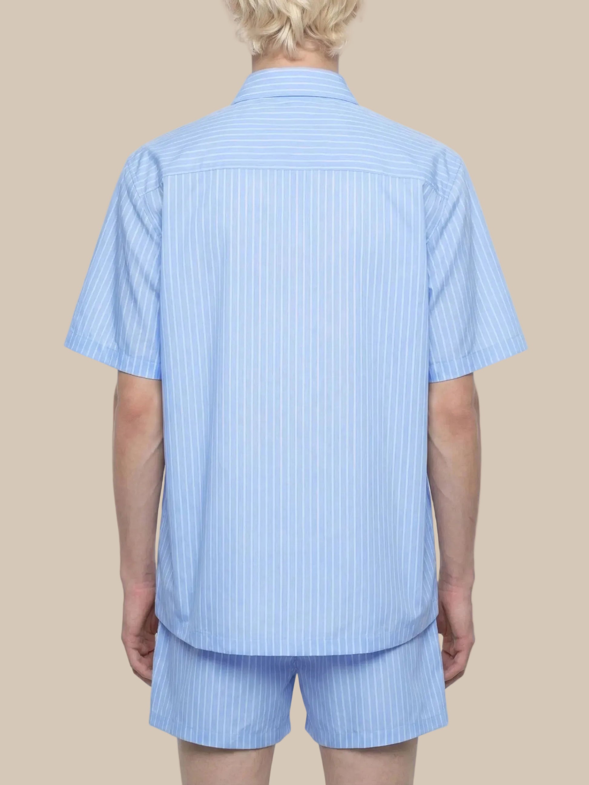 Person wearing a light blue striped shirt and shorts set on a white background