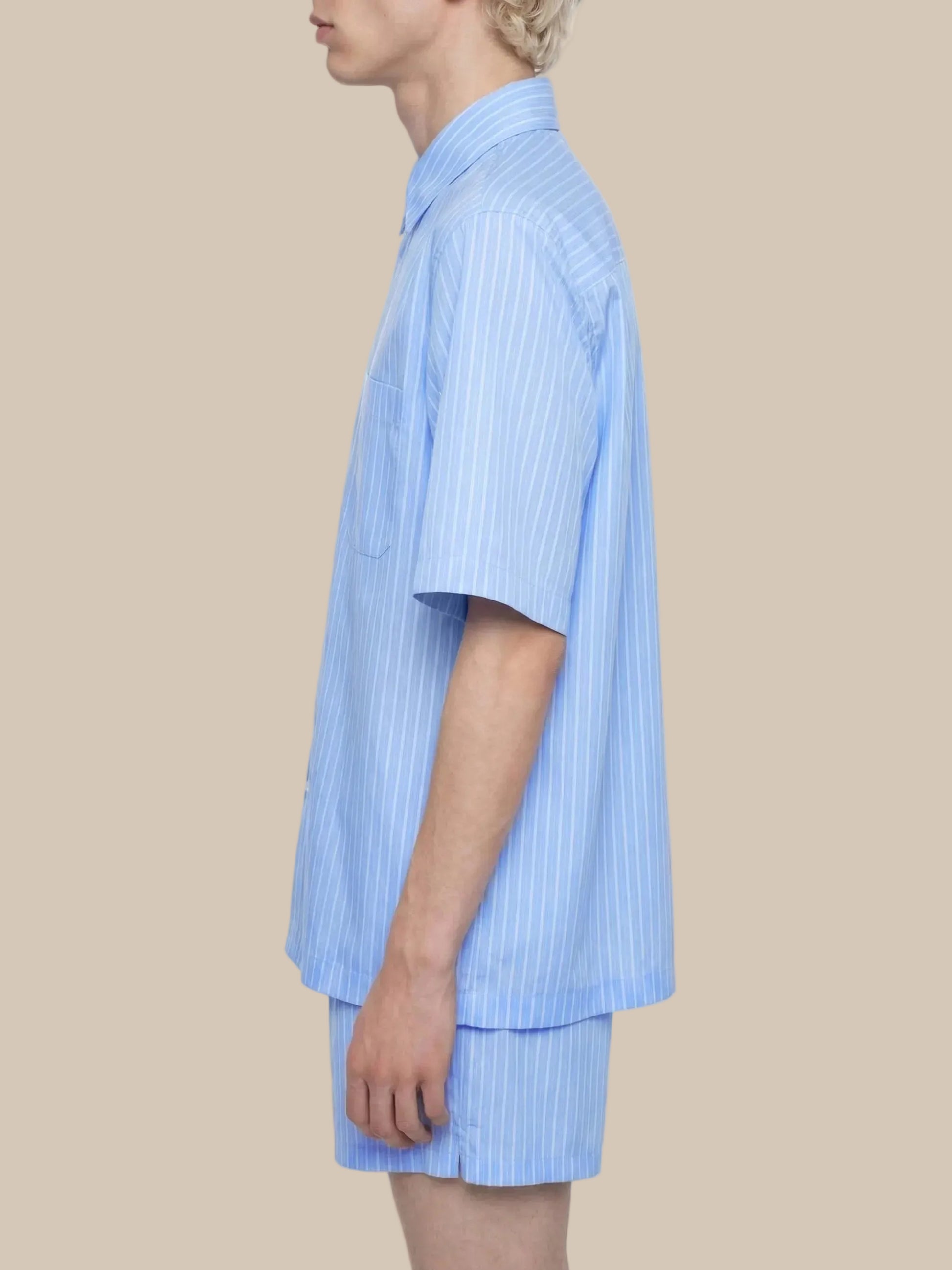 Person wearing a light blue striped shirt and shorts on a white background