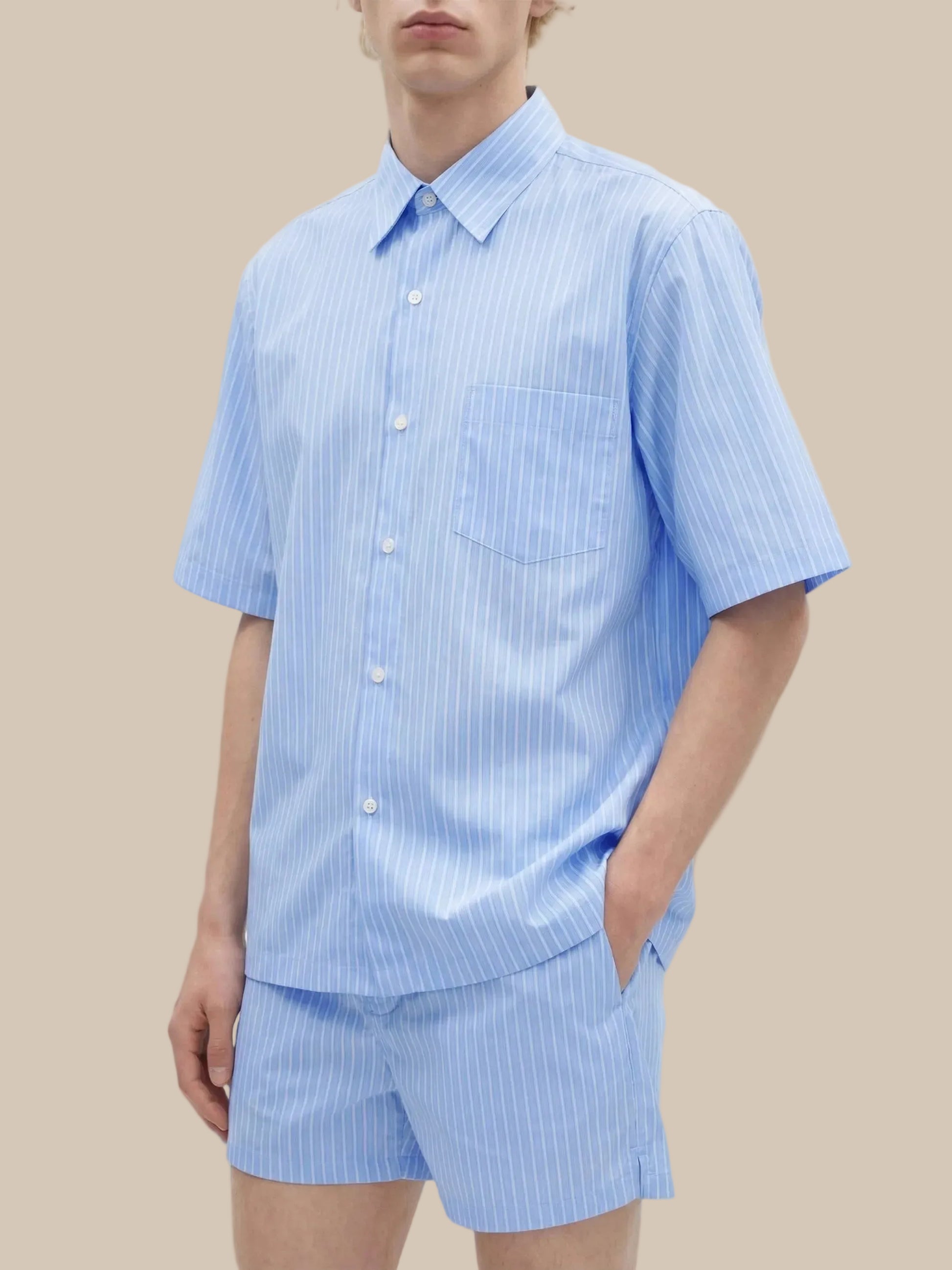 Person wearing a light blue striped shirt and shorts set on a white background