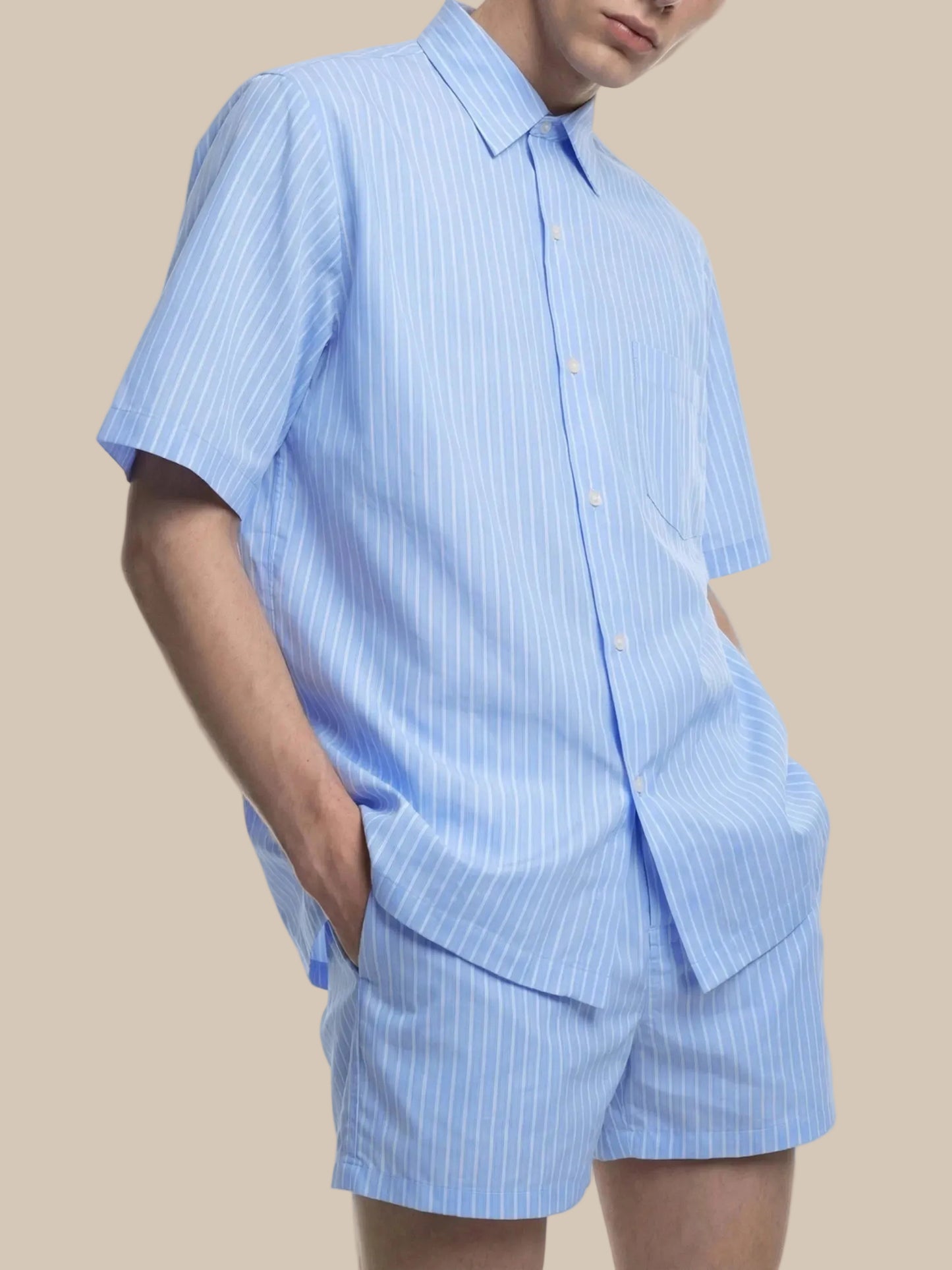 Person wearing a light blue striped shirt and shorts on a white background