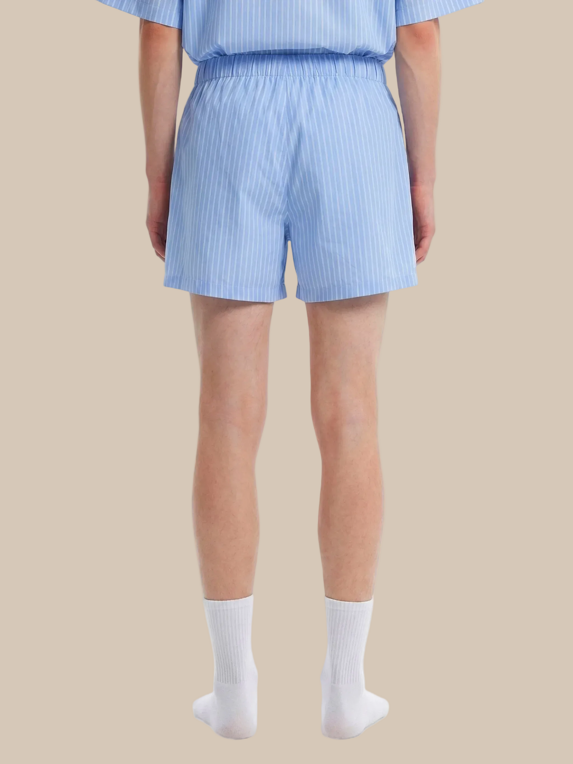 Person wearing light blue striped shorts and a matching top on a white background