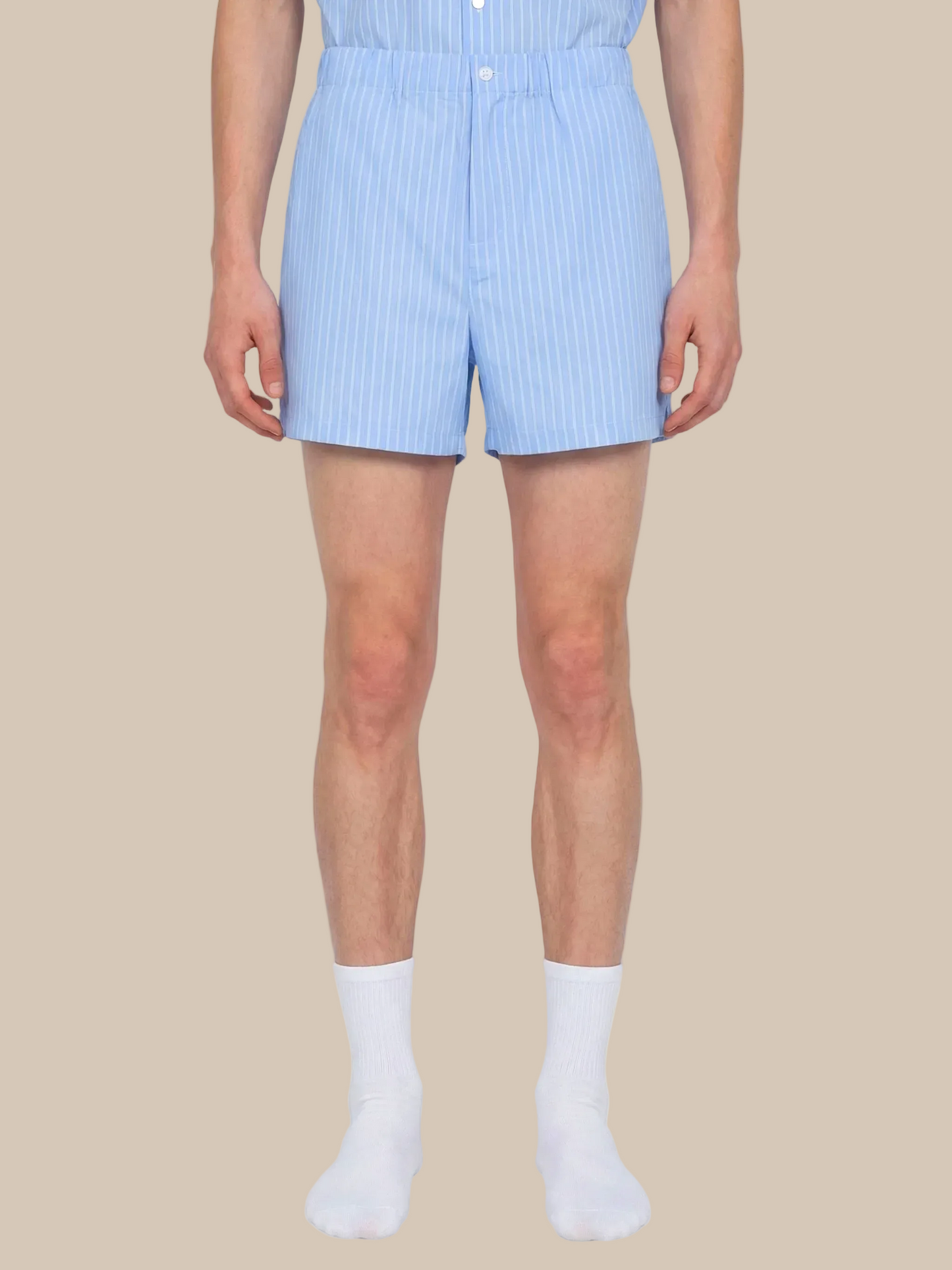 Person wearing light blue striped shorts on a white background