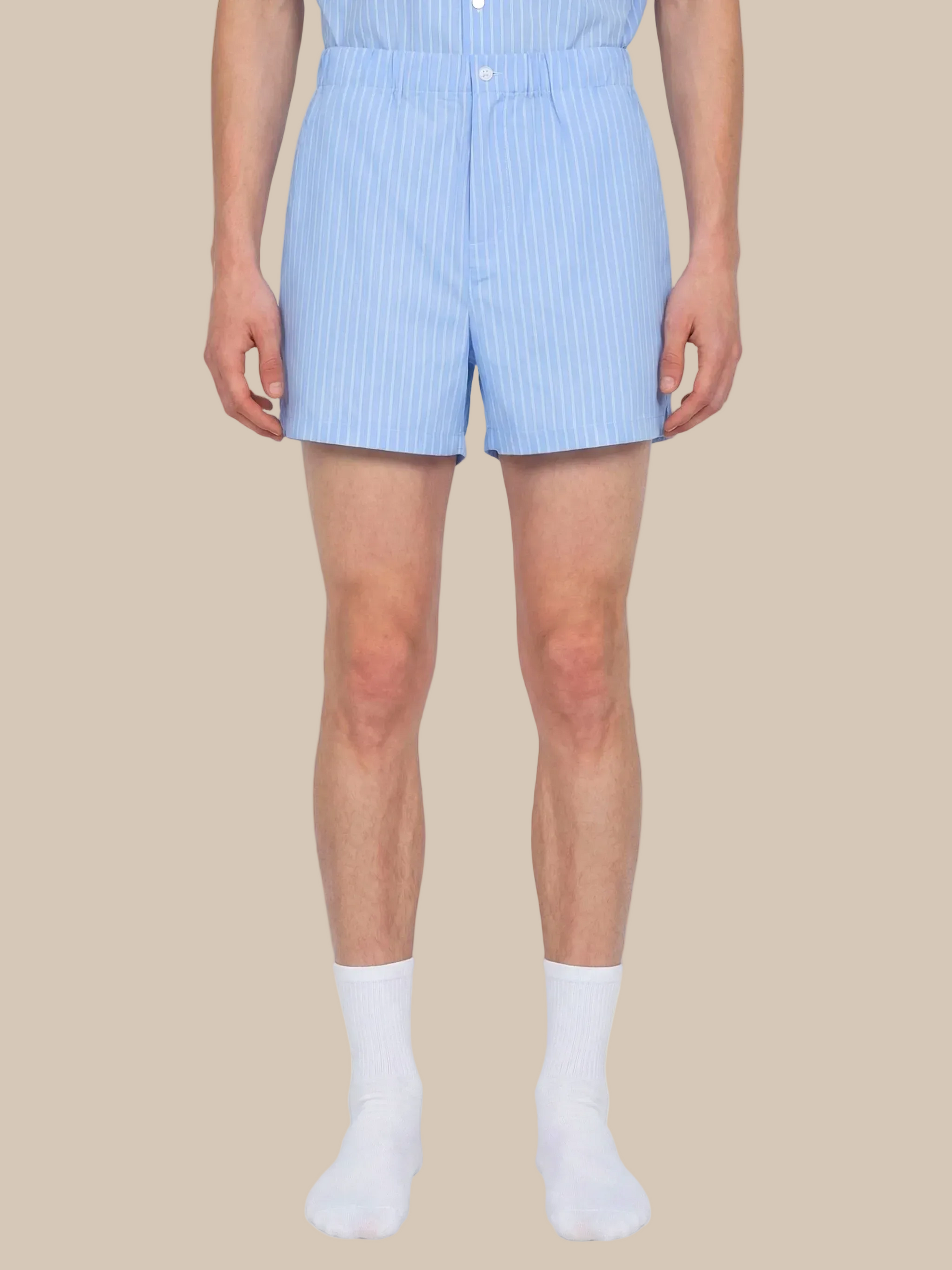 Person wearing light blue striped shorts on a white background
