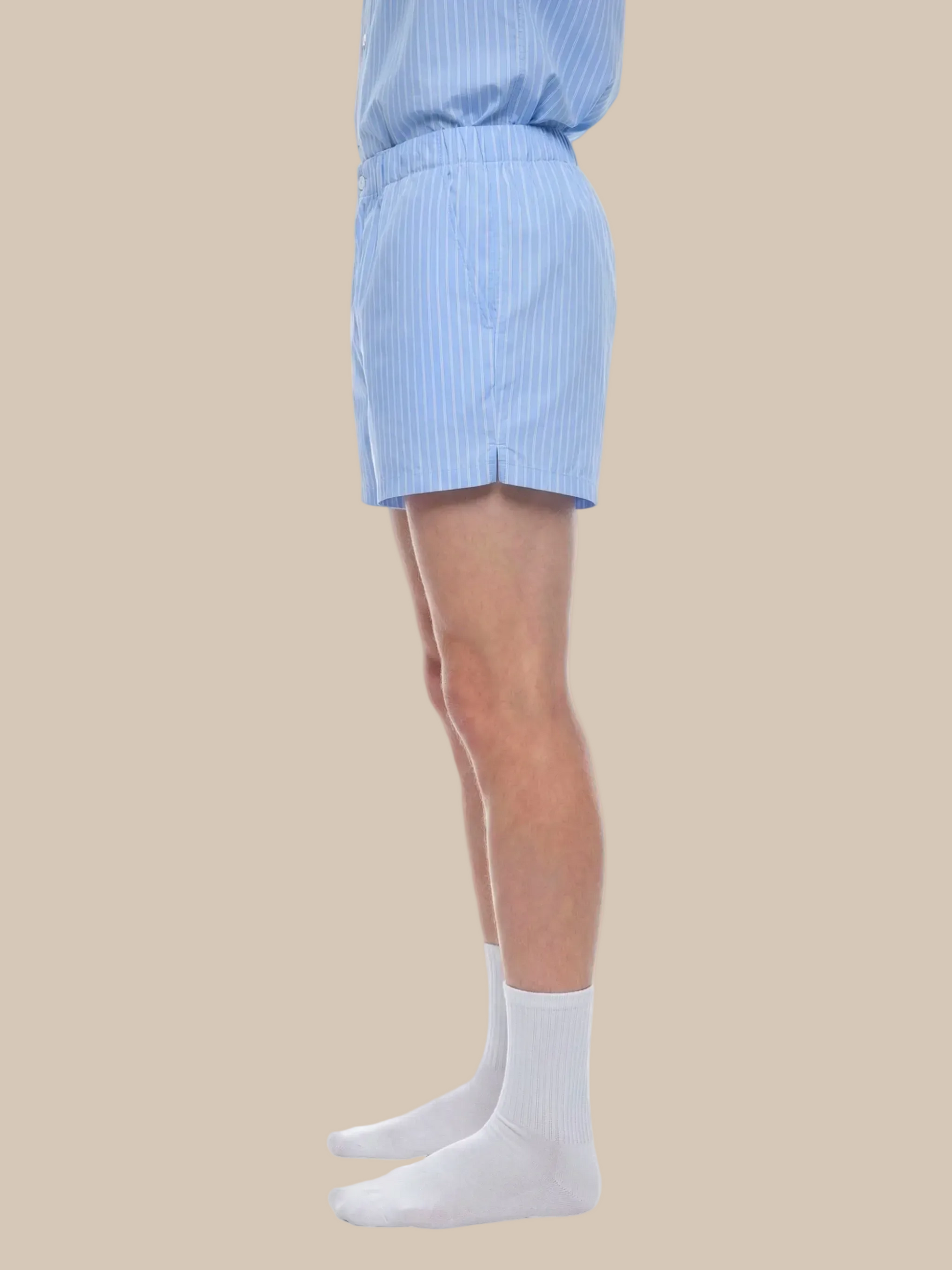 Person wearing light blue striped shorts and white socks on a white background