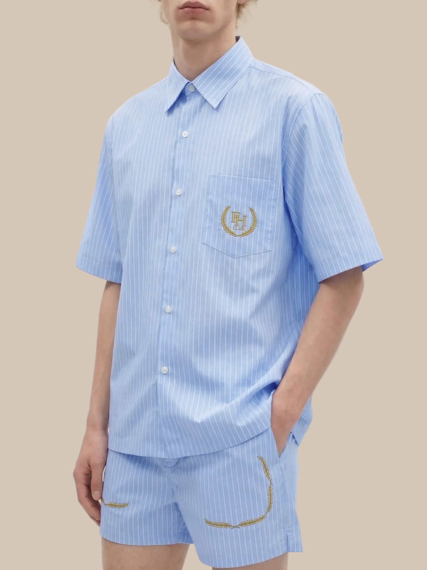 Person wearing a light blue striped shirt and shorts set with a logo on a white background
