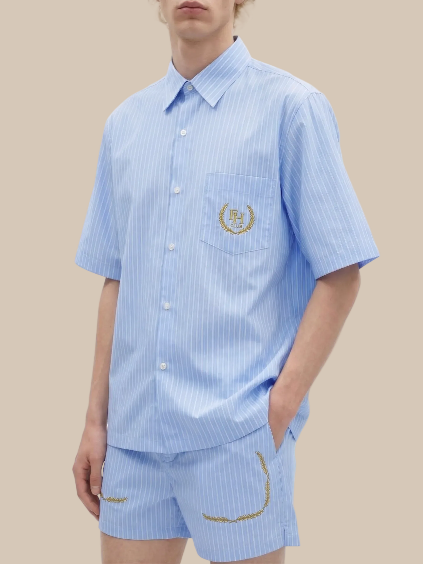 Person wearing a light blue striped shirt and shorts set with a logo on a white background