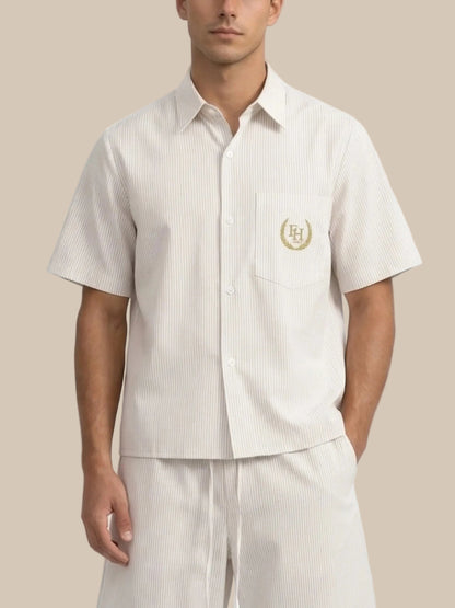Man wearing a white short-sleeve shirt with a logo and matching pants on a white background