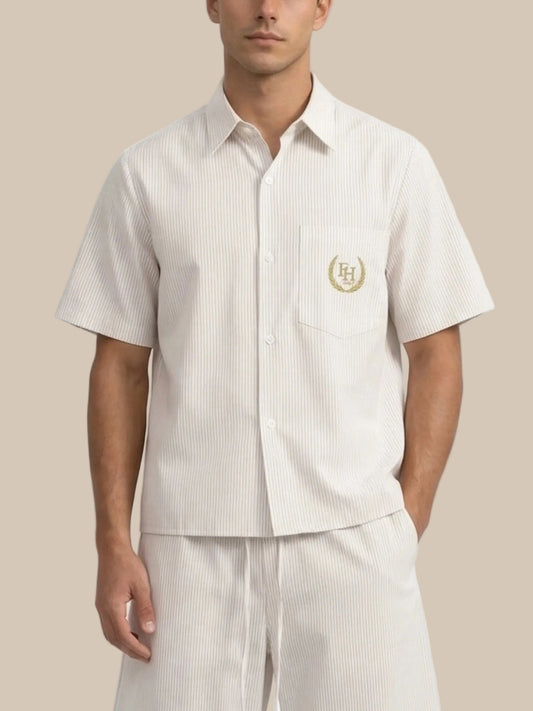 Man wearing a white short-sleeve shirt with a logo and matching pants on a white background