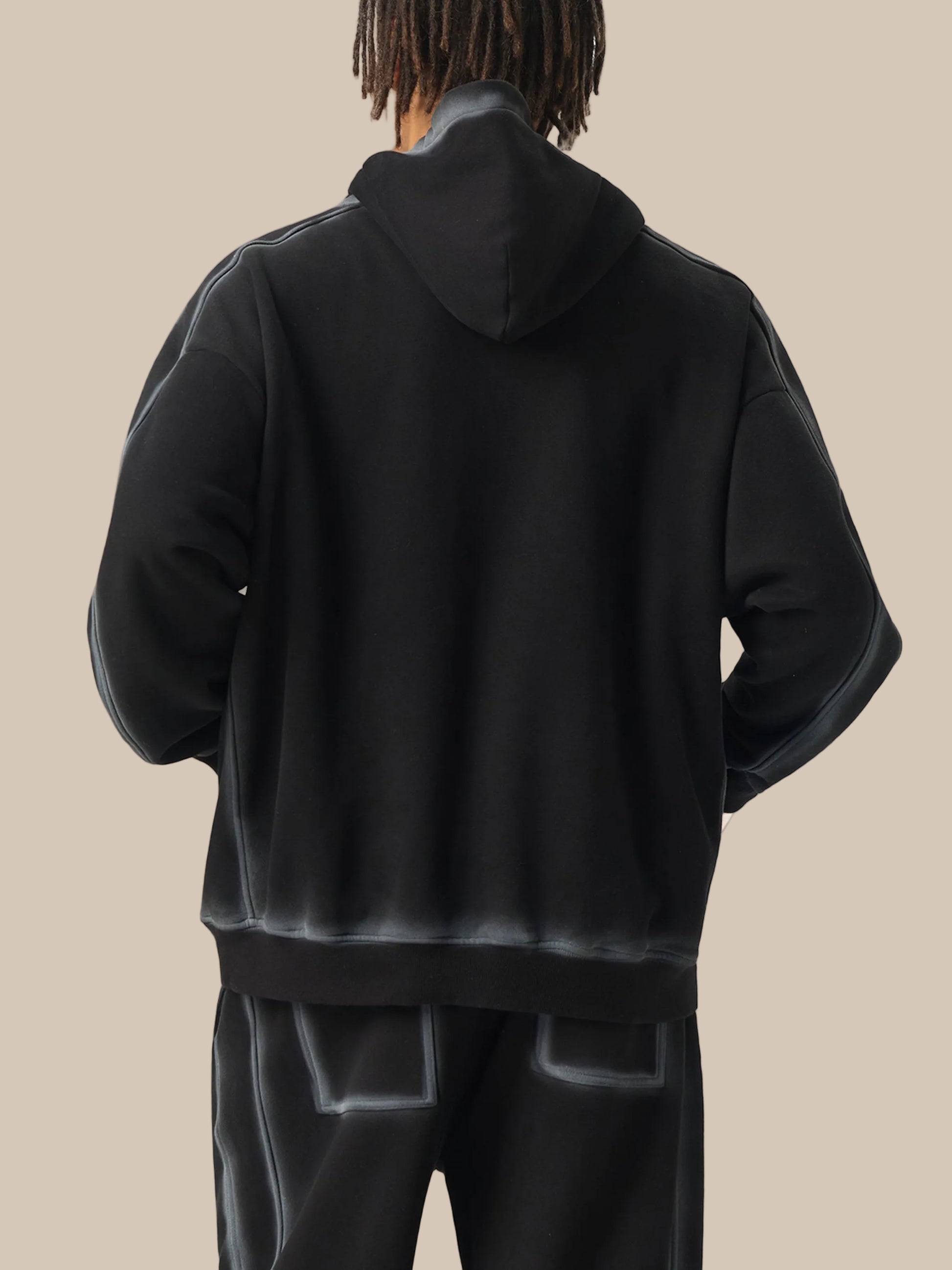 Person wearing a black hoodie and pants on a white background