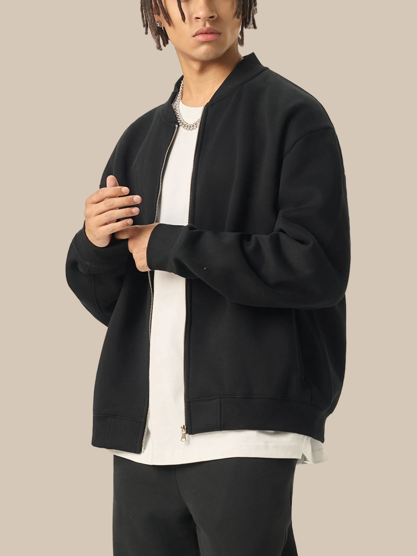 Person wearing a black bomber jacket over a white shirt on a white background