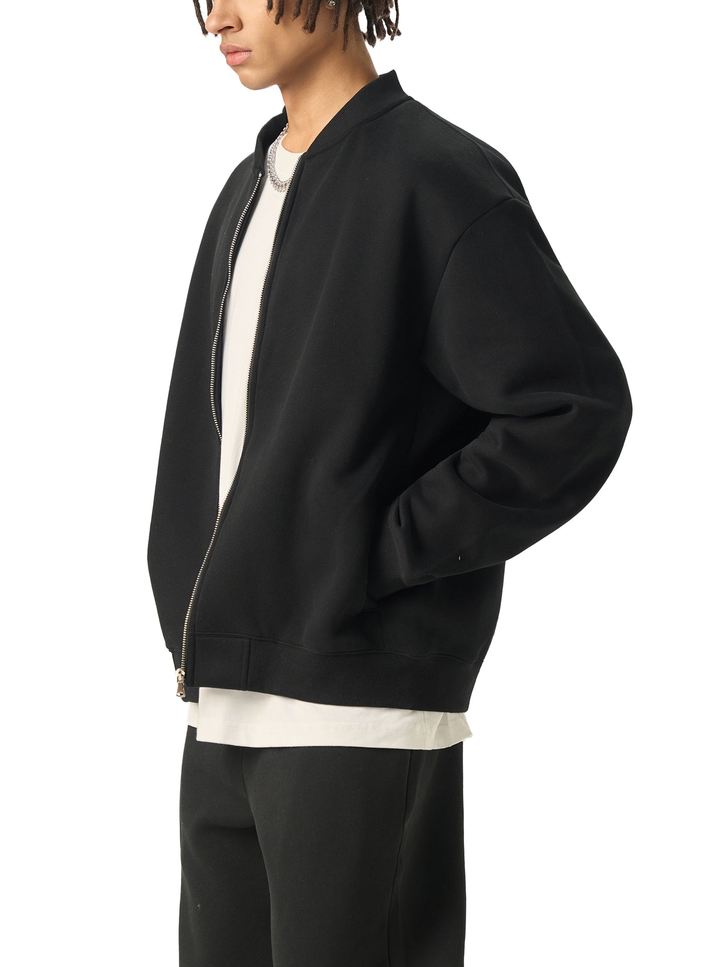 A Future-Homme model wearing the Fleece Please Varsity jacket in black side view on a white background. 