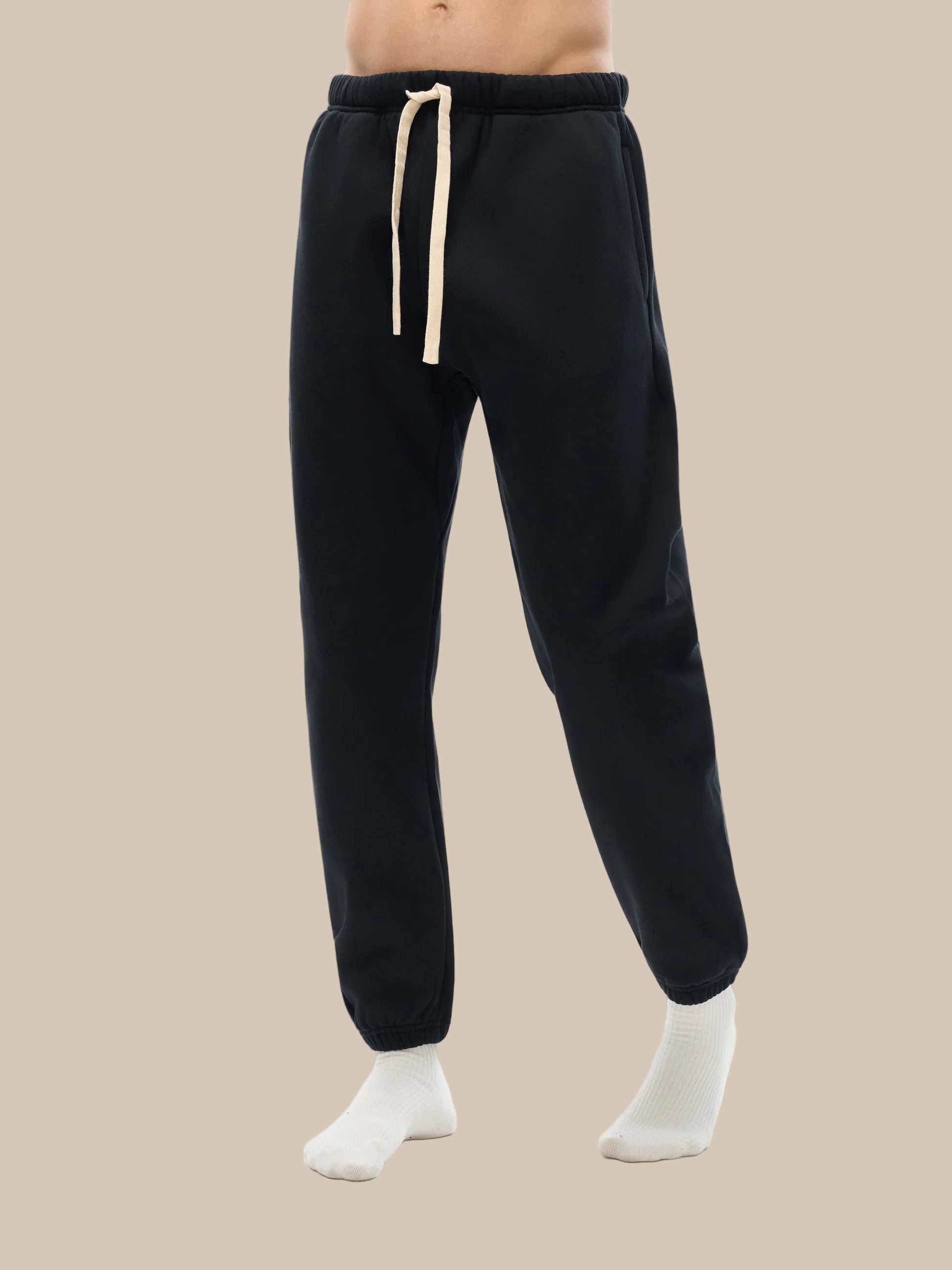 Black sweatpants with a beige drawstring on a white background