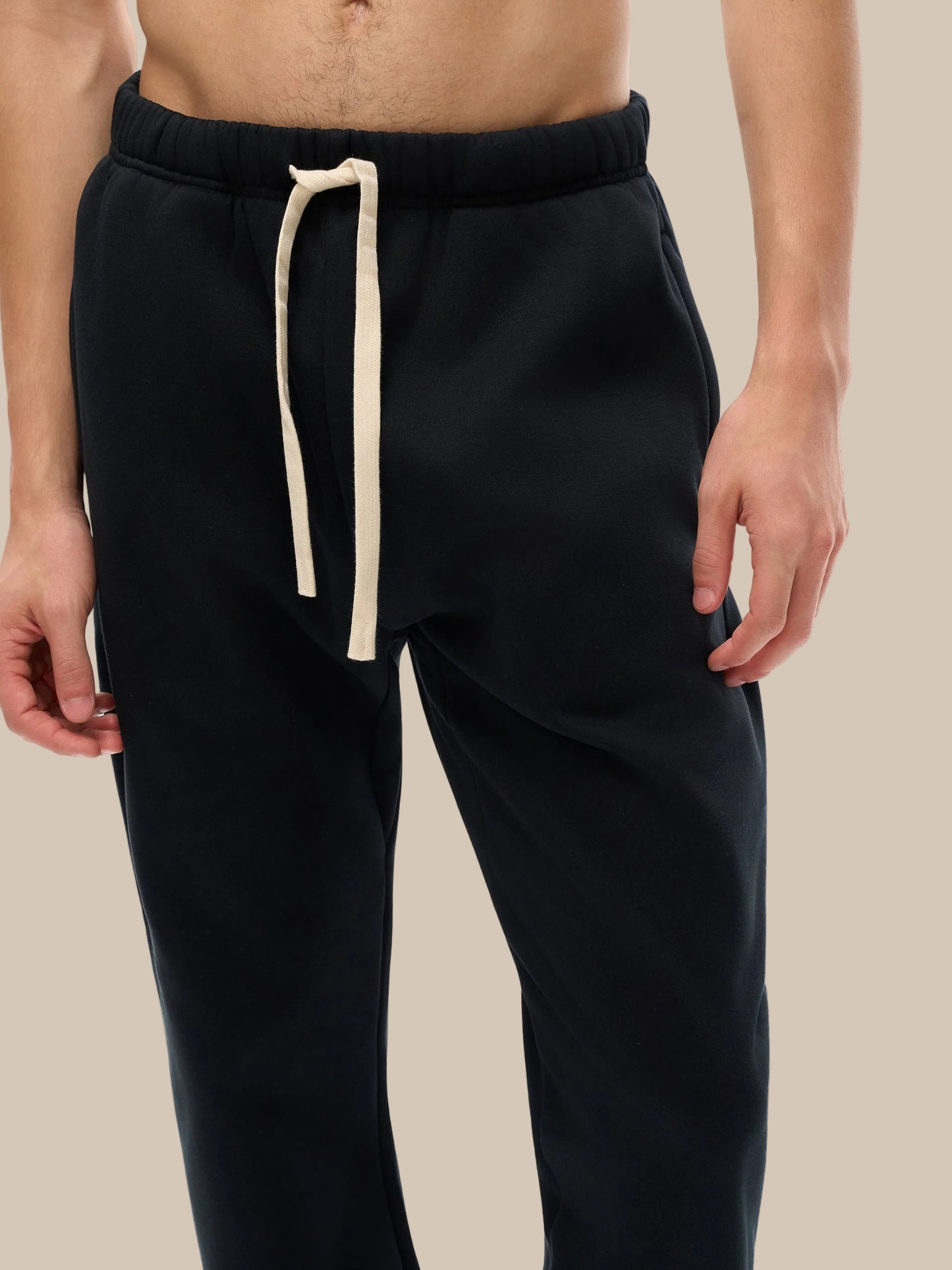 Black pants with a beige drawstring on a white background