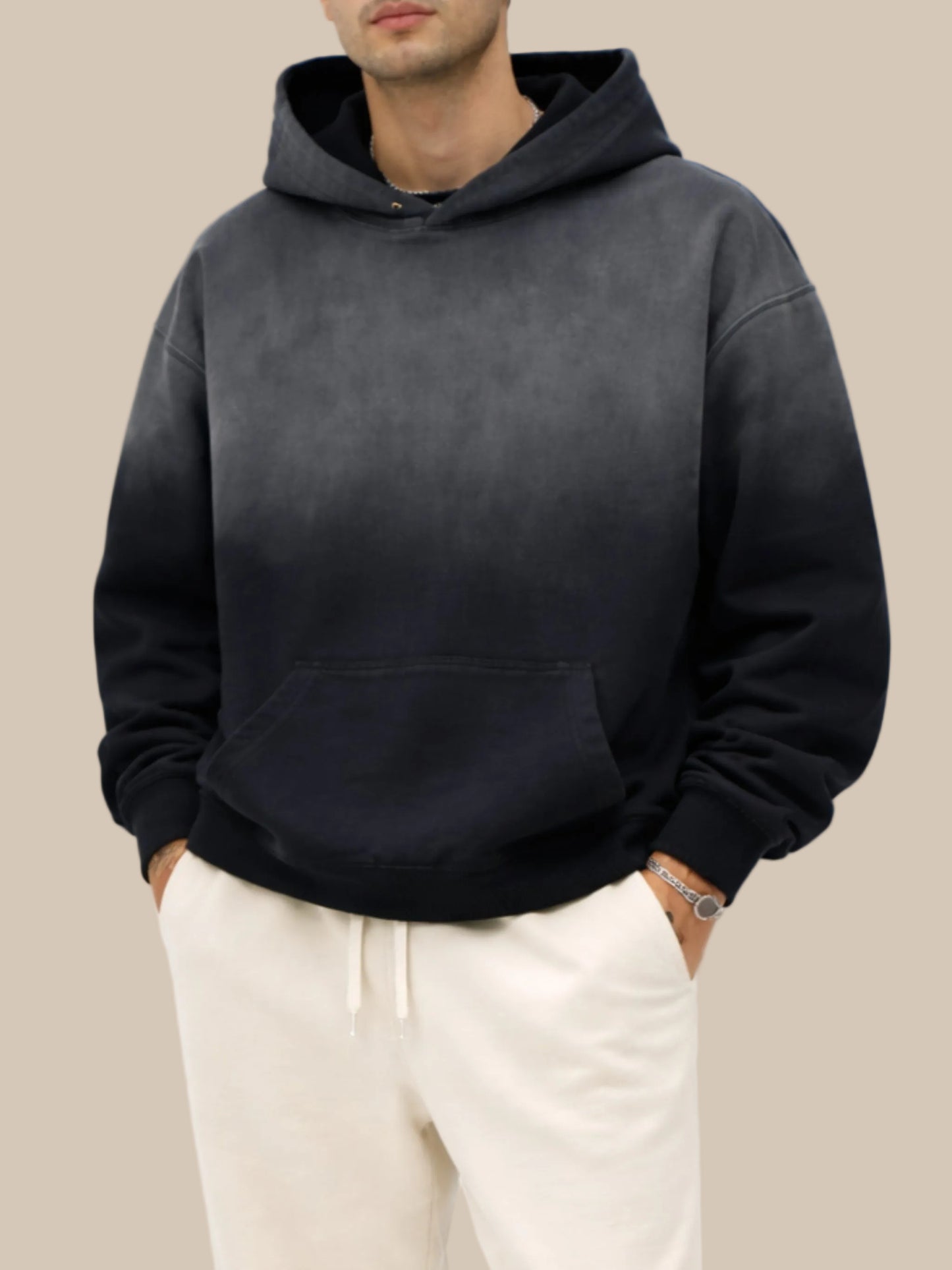 Person wearing a black hoodie and light-colored pants on a white background