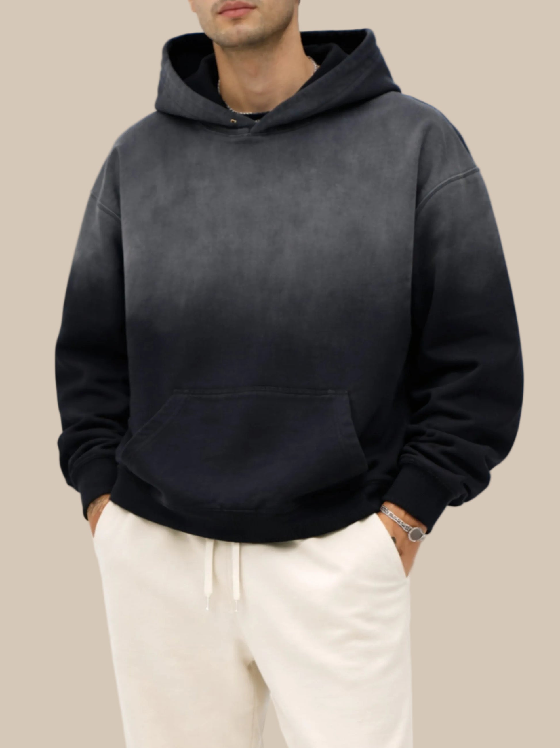 Person wearing a black hoodie and light-colored pants on a white background