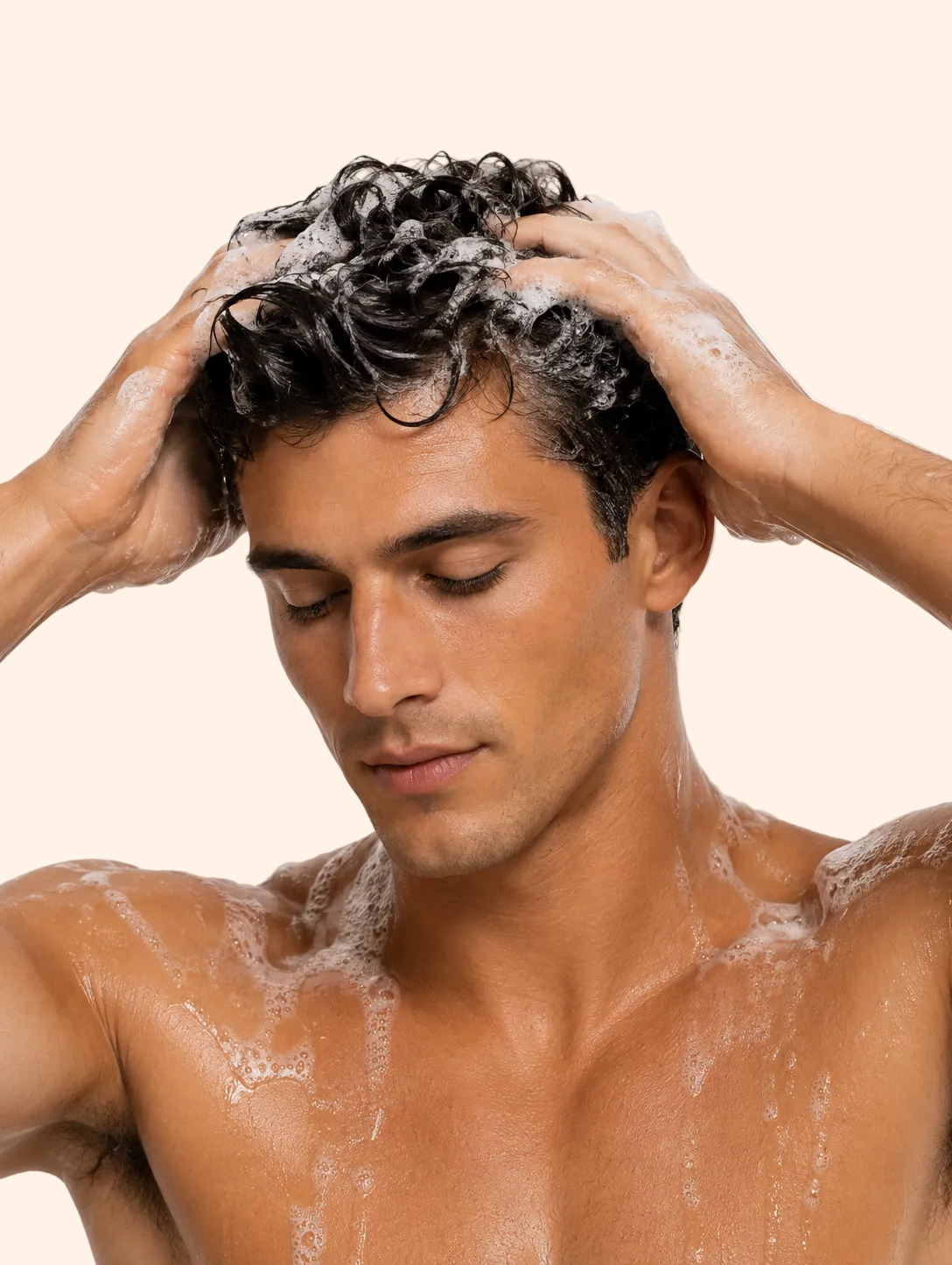 Man washing his hair with shampoo against a plain background