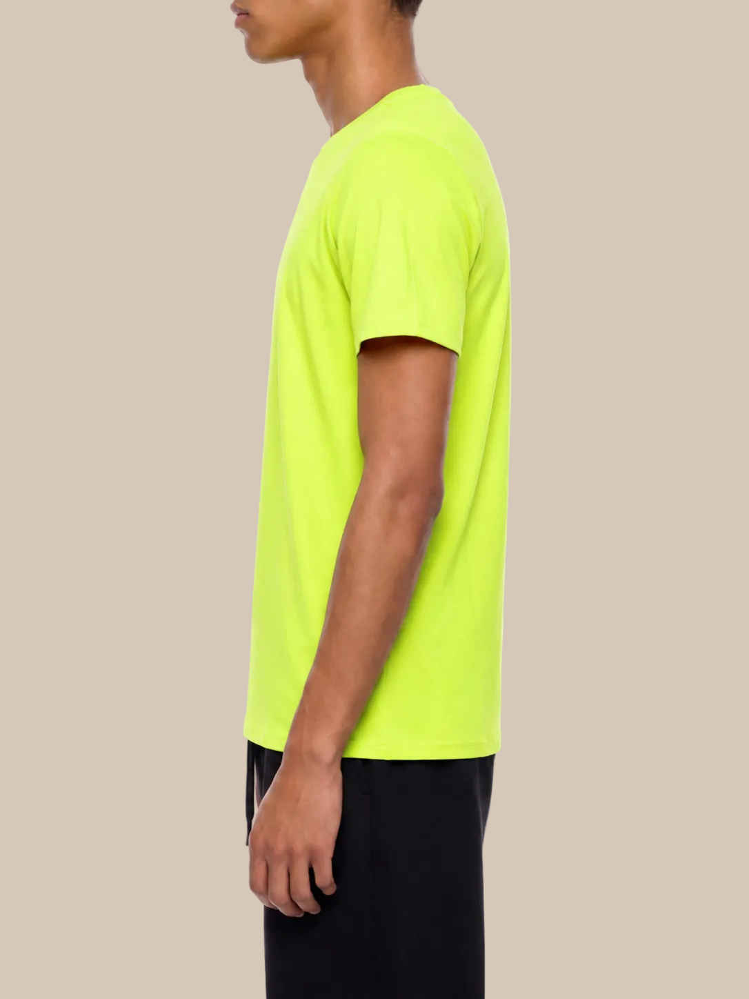 Side profile of a person wearing a bright green performance t-shirt on a beige background. 
