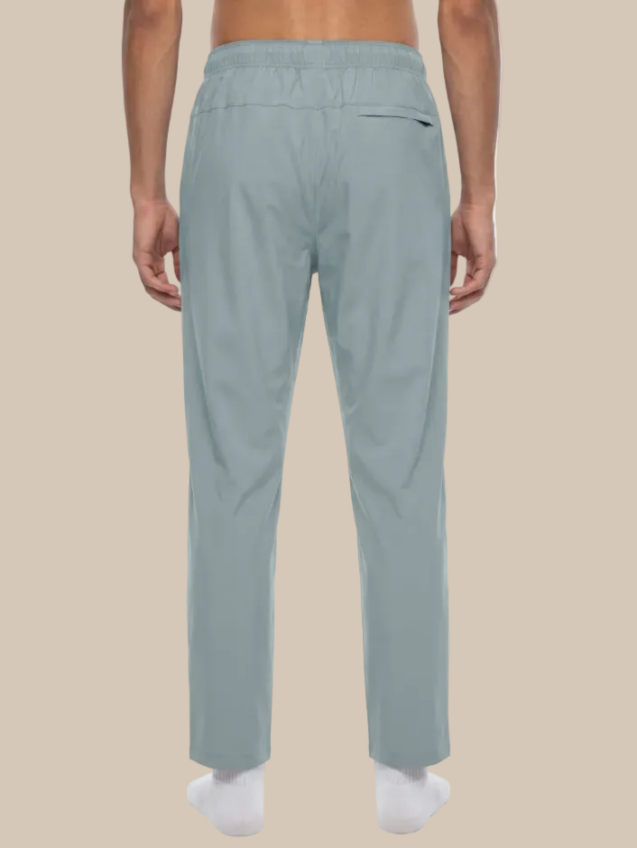 Gray blue track pants worn by a person on a beige background