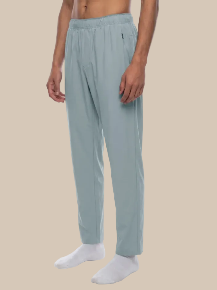 Person wearing light blue track pants on a beige background